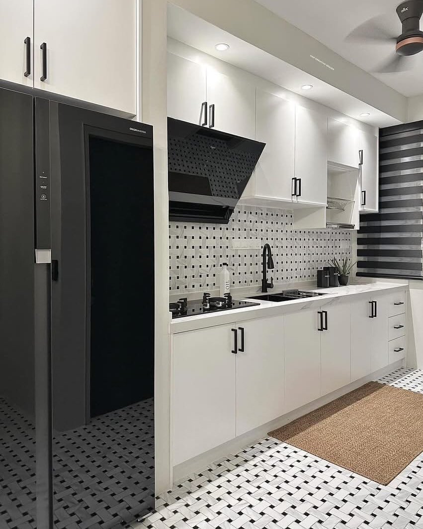 A modern kitchen with white cabinets, a black and white tiled backsplash and floor, and black hardware.