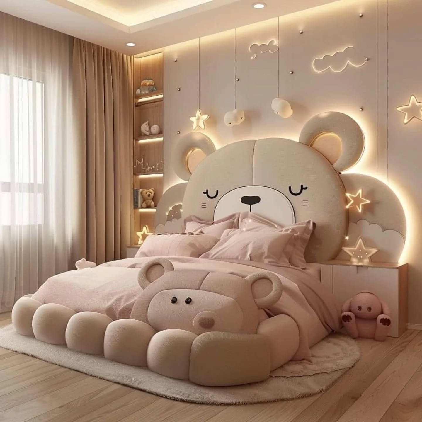 A kid's bedroom with a large, plush bed shaped like a giant teddy bear. The headboard is the bear's head with ears and a face, and the footboard is the bear's body and paws. The room is decorated in soft pinks and creams, with star and cloud-shaped wall lights.