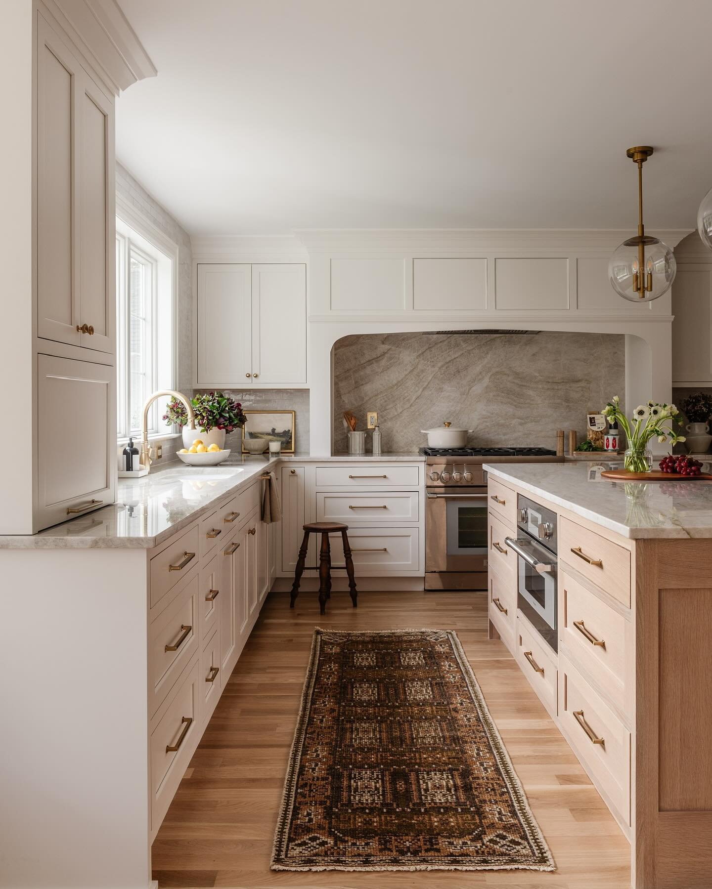 A spacious kitchen featuring a large island with light wood cabinets and perimeter cabinetry in a soft off-white color.