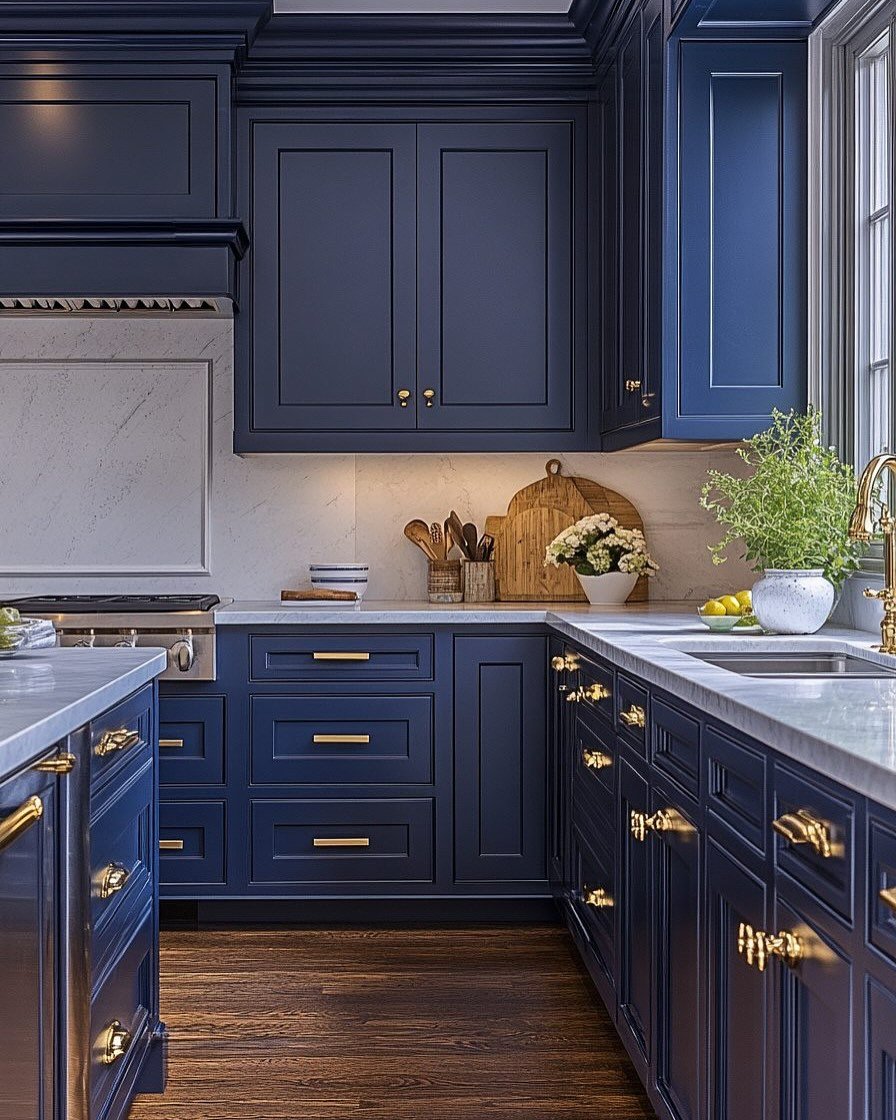 A luxurious kitchen with deep navy blue shaker-style cabinets, marble countertops, and gold hardware.