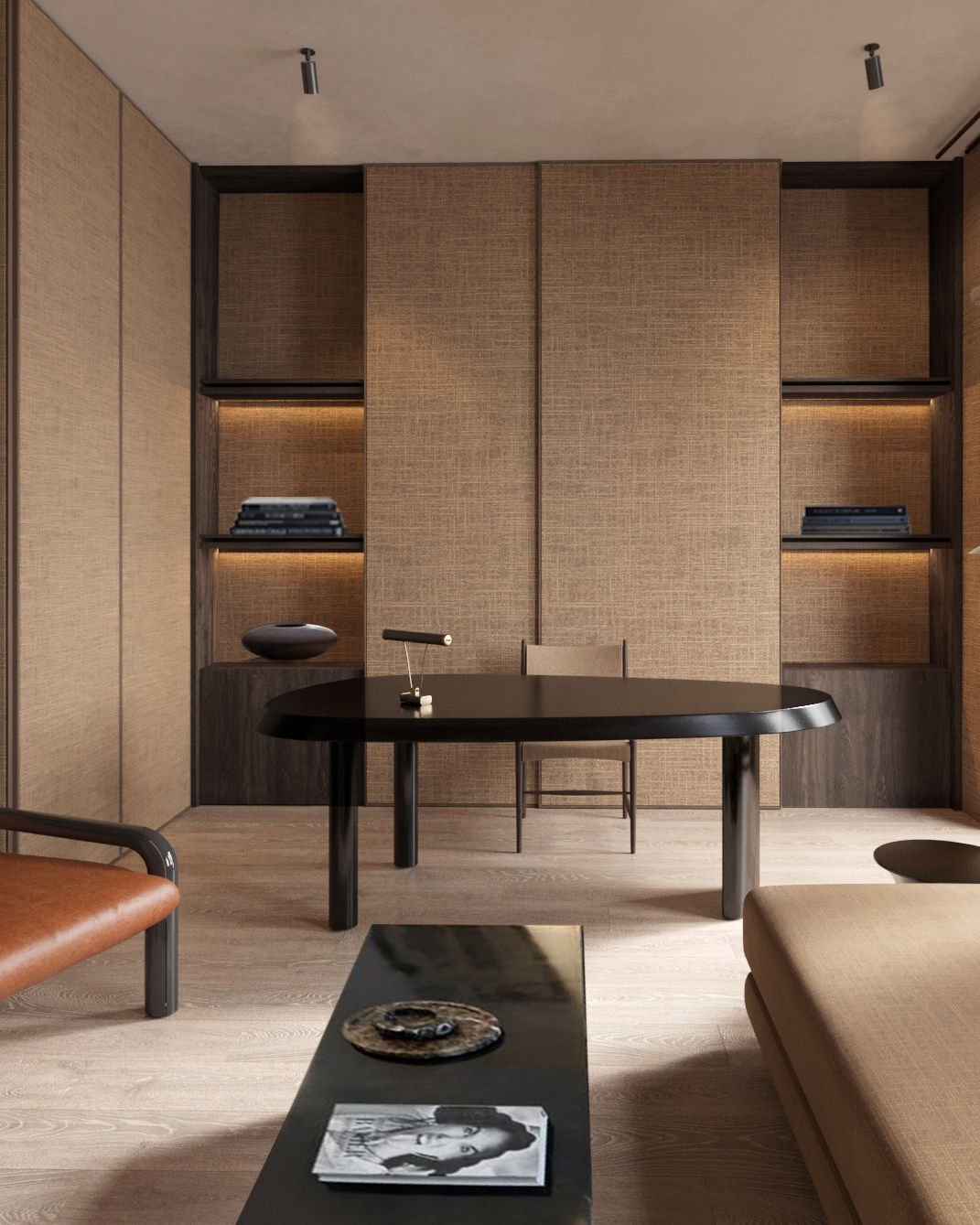 A sculptural, minimalist study desk with a rounded black tabletop, a simple chair, and a built-in wall unit with textured panels and illuminated shelves.