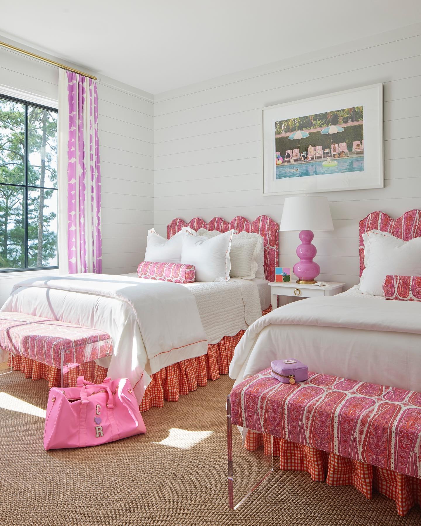 A bright and preppy shared bedroom with twin beds featuring scallop-edged pink headboards and matching benches, set against a white shiplap wall.