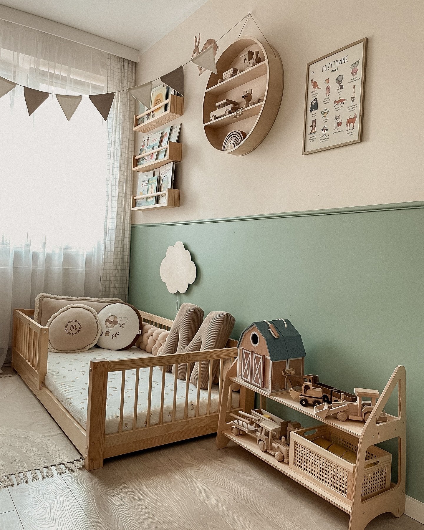 A playful toddler room with a low wood bed, a green and beige wall, and natural wood toys on a shelf.
