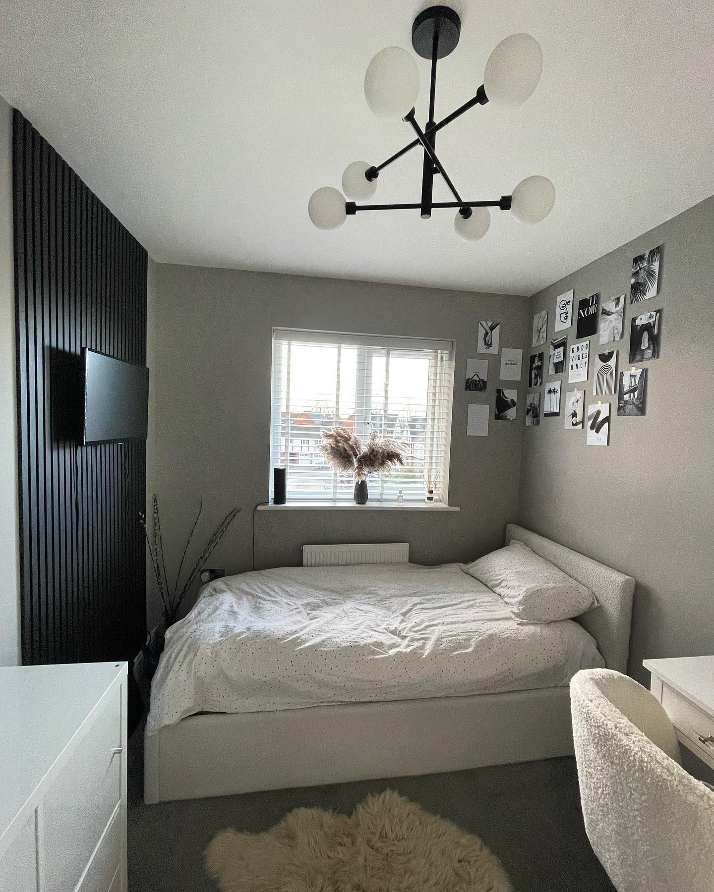 A small, modern teen bedroom with a gray and black color scheme, featuring a slatted wood accent wall and a gallery of black and white photos.