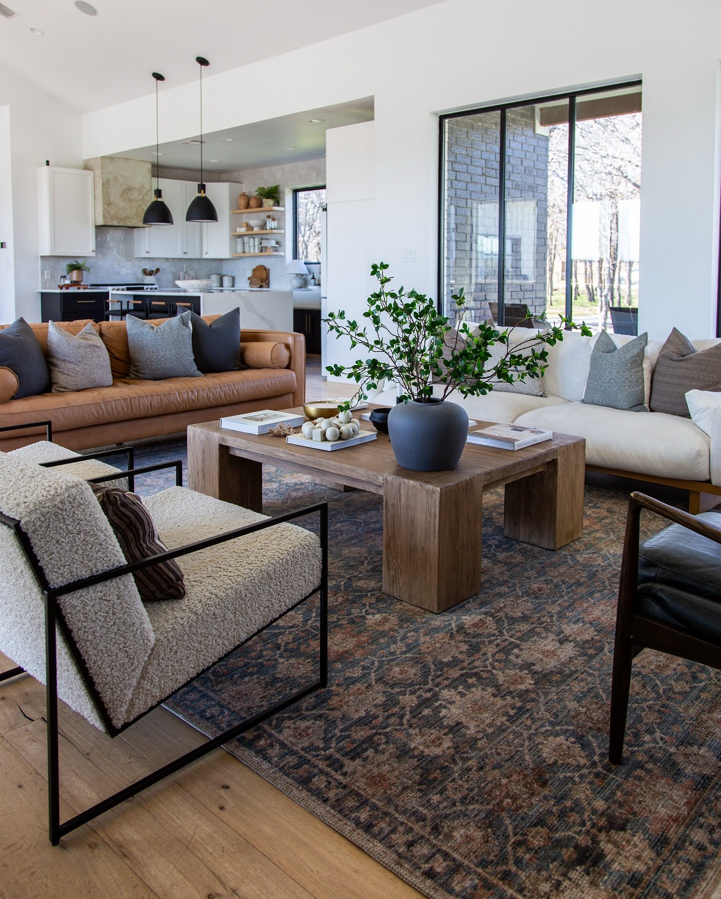 A dark, richly patterned vintage rug with intricate motifs in navy, rust, and beige tones on a light wood floor.