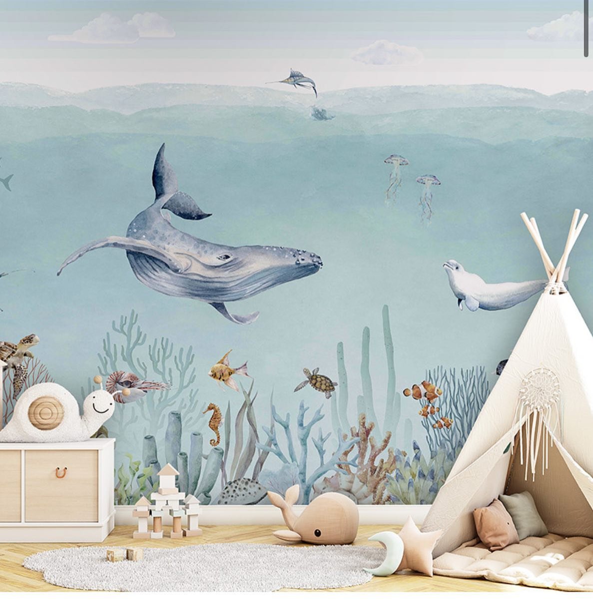A child's room with a vibrant mural of a whale, seal, and other sea life in a coral reef, with a teepee play tent.