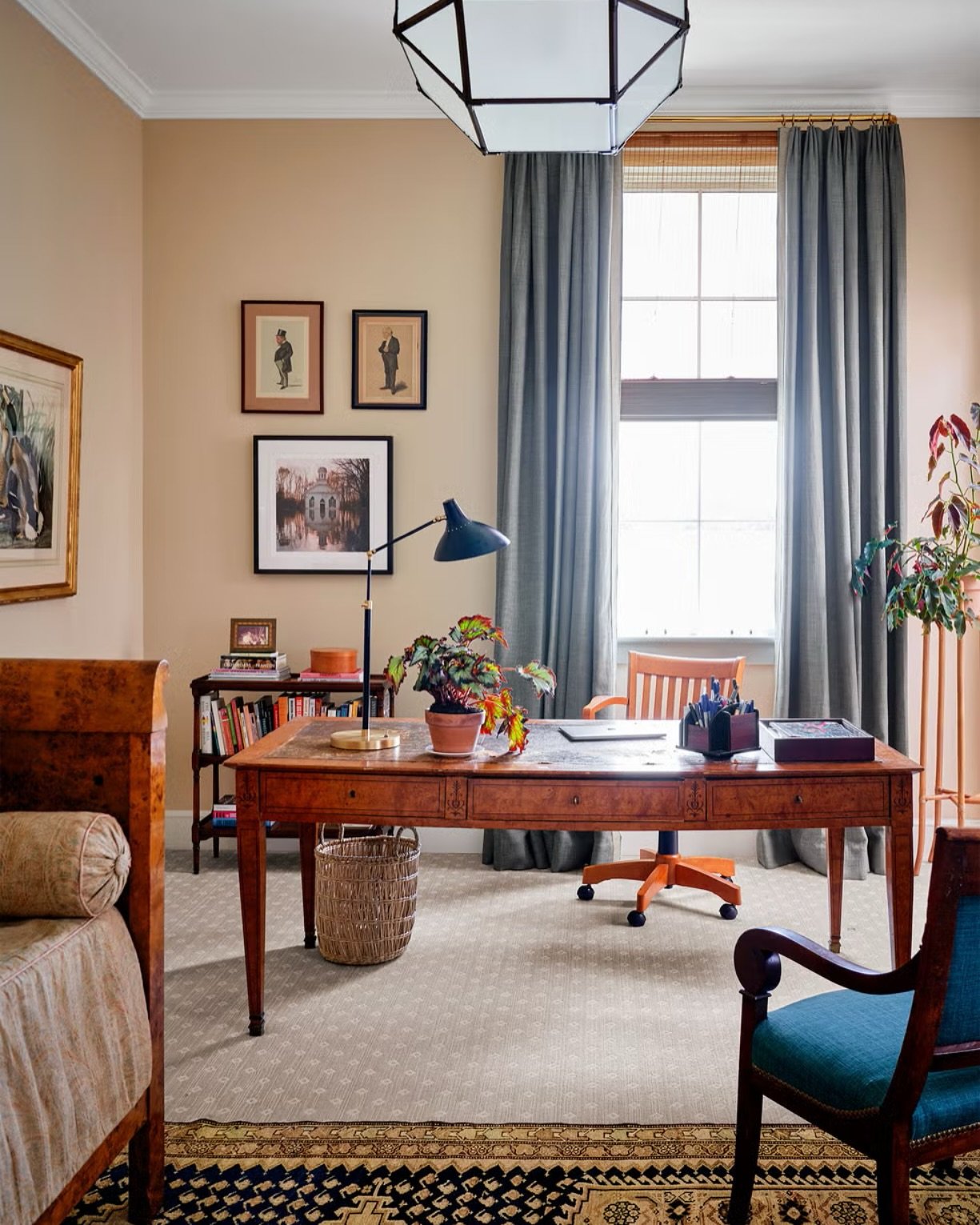 A stately, classic wooden study desk with three drawers, a leather inlay top, and an orange-seated rolling chair.