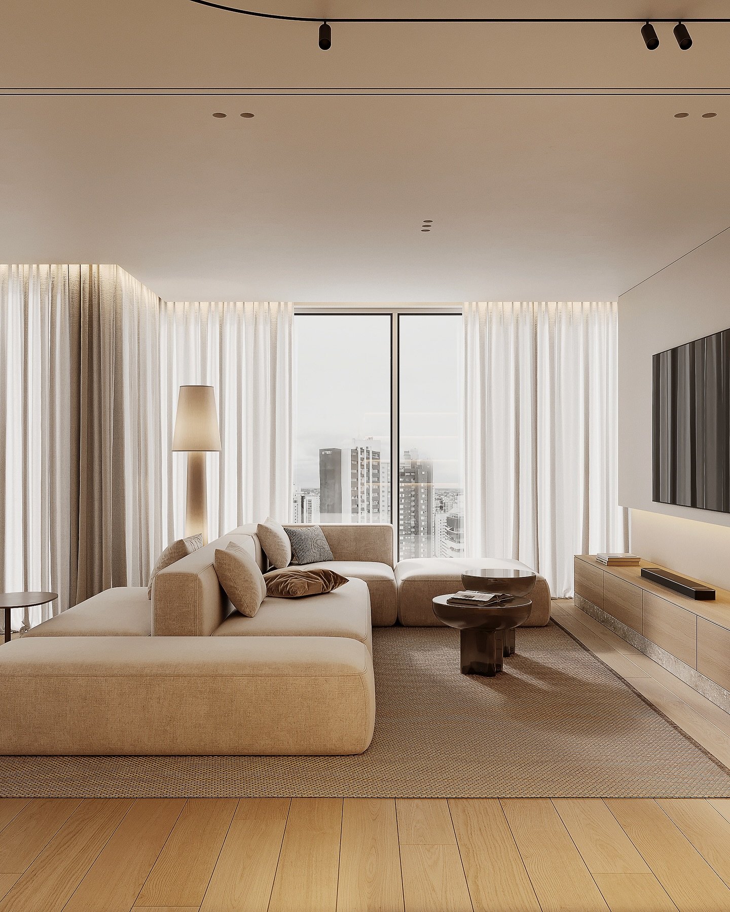 A bright and minimalist living room with a large, beige modular sofa, a low-profile media console, and floor-to-ceiling windows with sheer white curtains overlooking a city skyline.