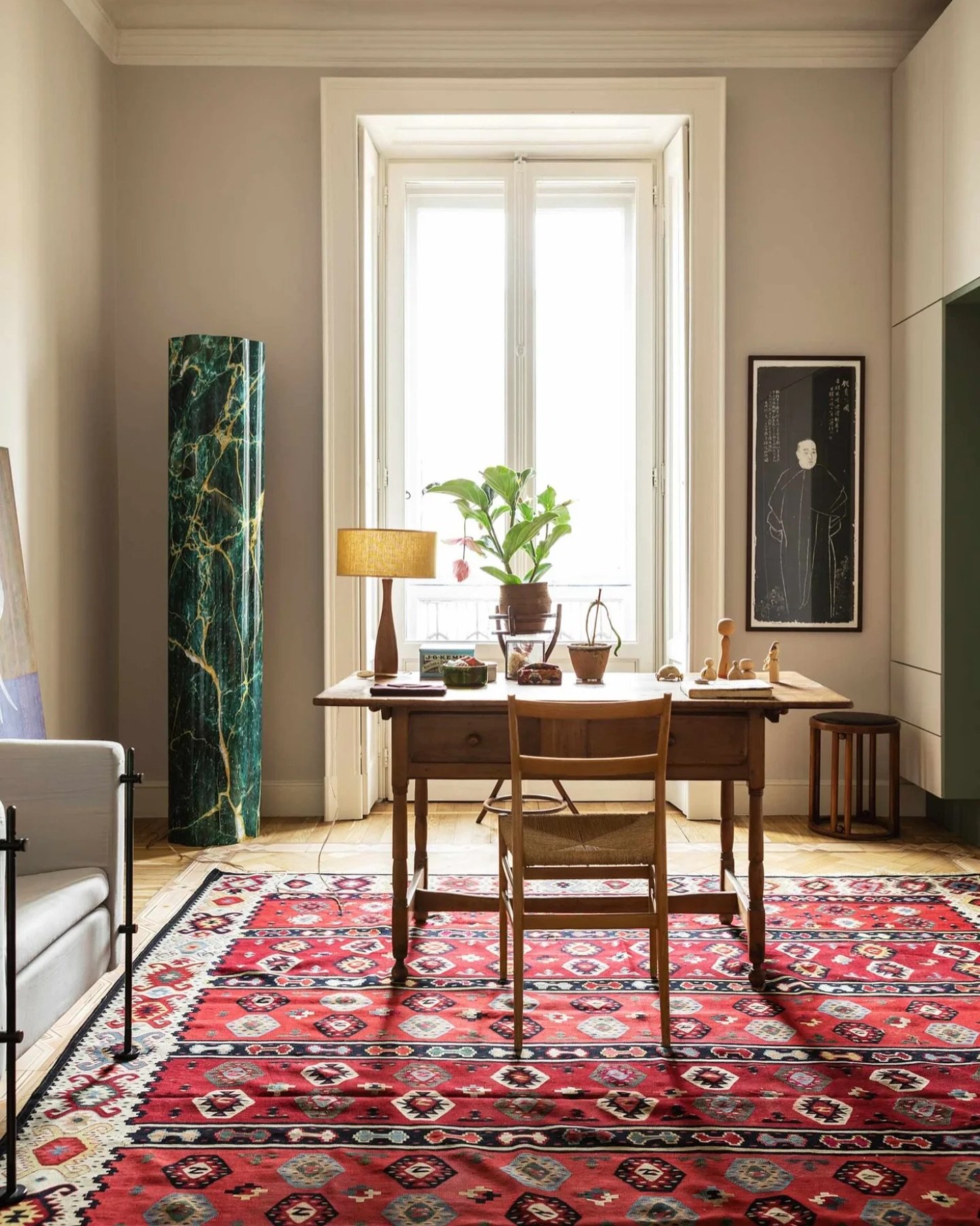 A charming vintage wooden writing desk with a single drawer, a wooden chair with a woven seat, and a lamp with a fringed shade.