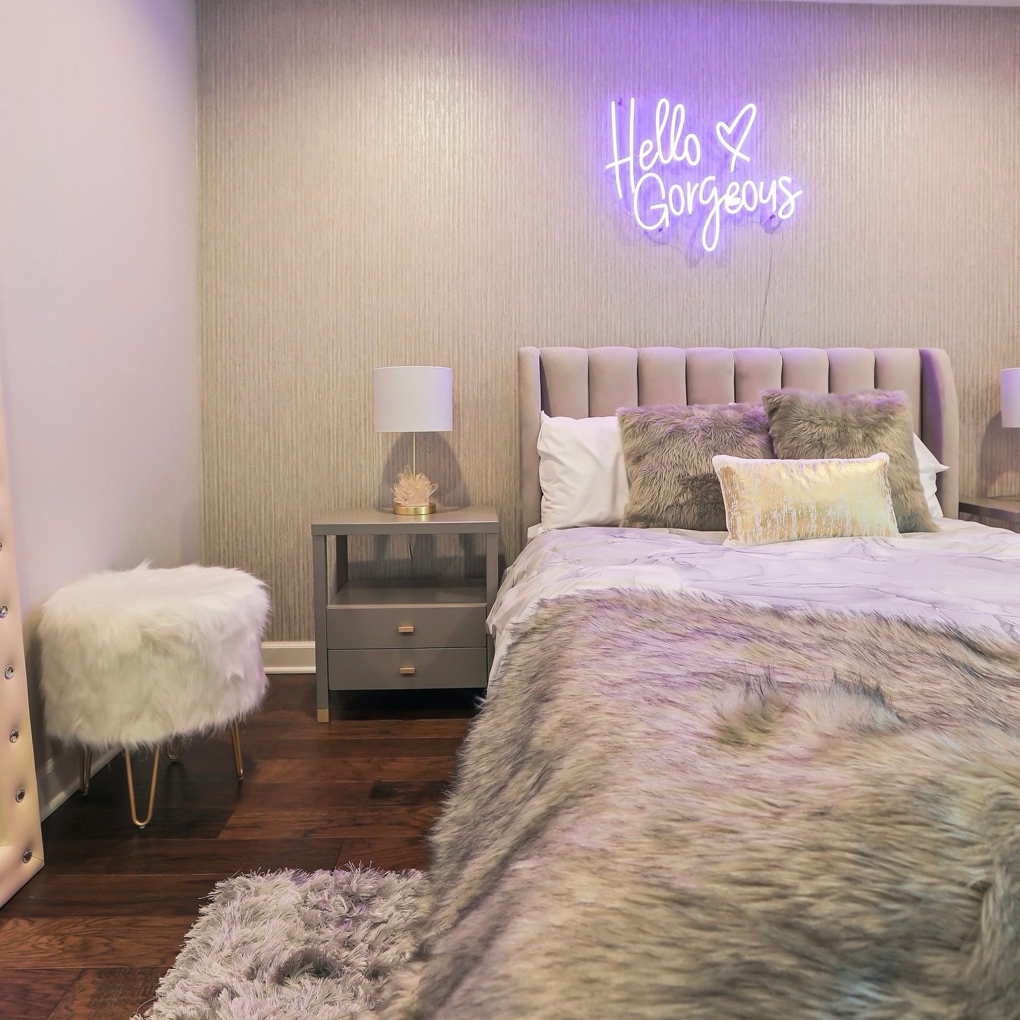 A stylish teen girl's bedroom with a gray and lilac color scheme, a tufted headboard, and a pink neon sign that says "Hello Gorgeous."