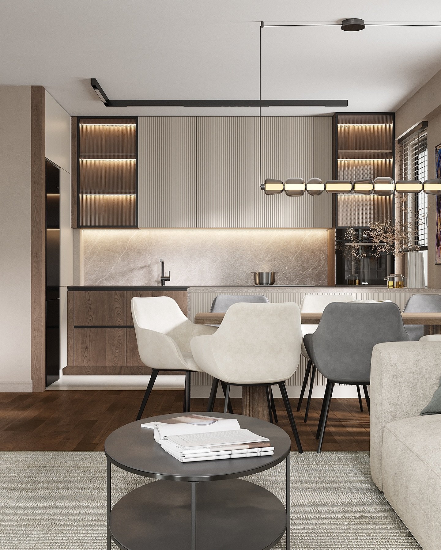 A view of a compact, modern open-concept space. The living area is in the foreground with a round coffee table and a sofa. The dining area features a wooden table with mixed-style chairs. The kitchen has a textured vertical panel backsplash, open shelving, and a marble countertop.