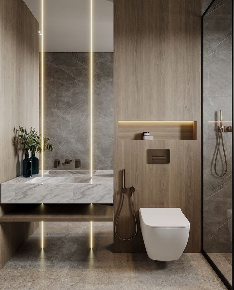 A small, contemporary bathroom with a floating marble sink, wood-paneled walls, and a floating toilet. Vertical LED lights are integrated into the mirror.