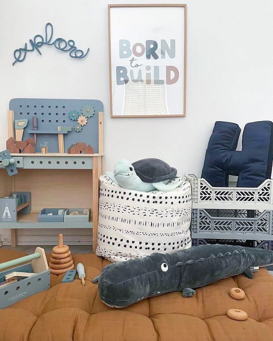 A child's room with a "Born to Build" poster, a small workbench, and stuffed toys including a turtle and a crocodile.