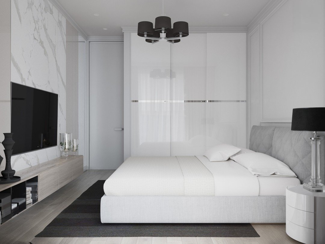 A modern bedroom with a white marble accent wall, a light gray upholstered bed with white bedding, and sleek sliding wardrobe doors.