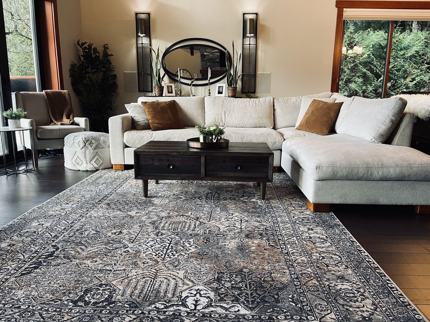 A large, traditional area rug with a dark gray, black, and white ornate medallion and border pattern on a dark wood floor.