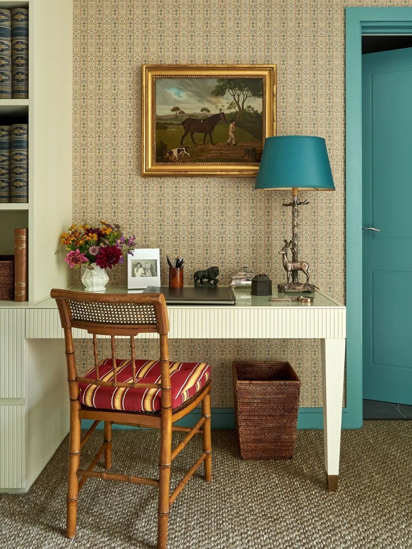 An elegant white study desk with a fluted front, blue-green legs, and a bamboo-style chair with a striped cushion.