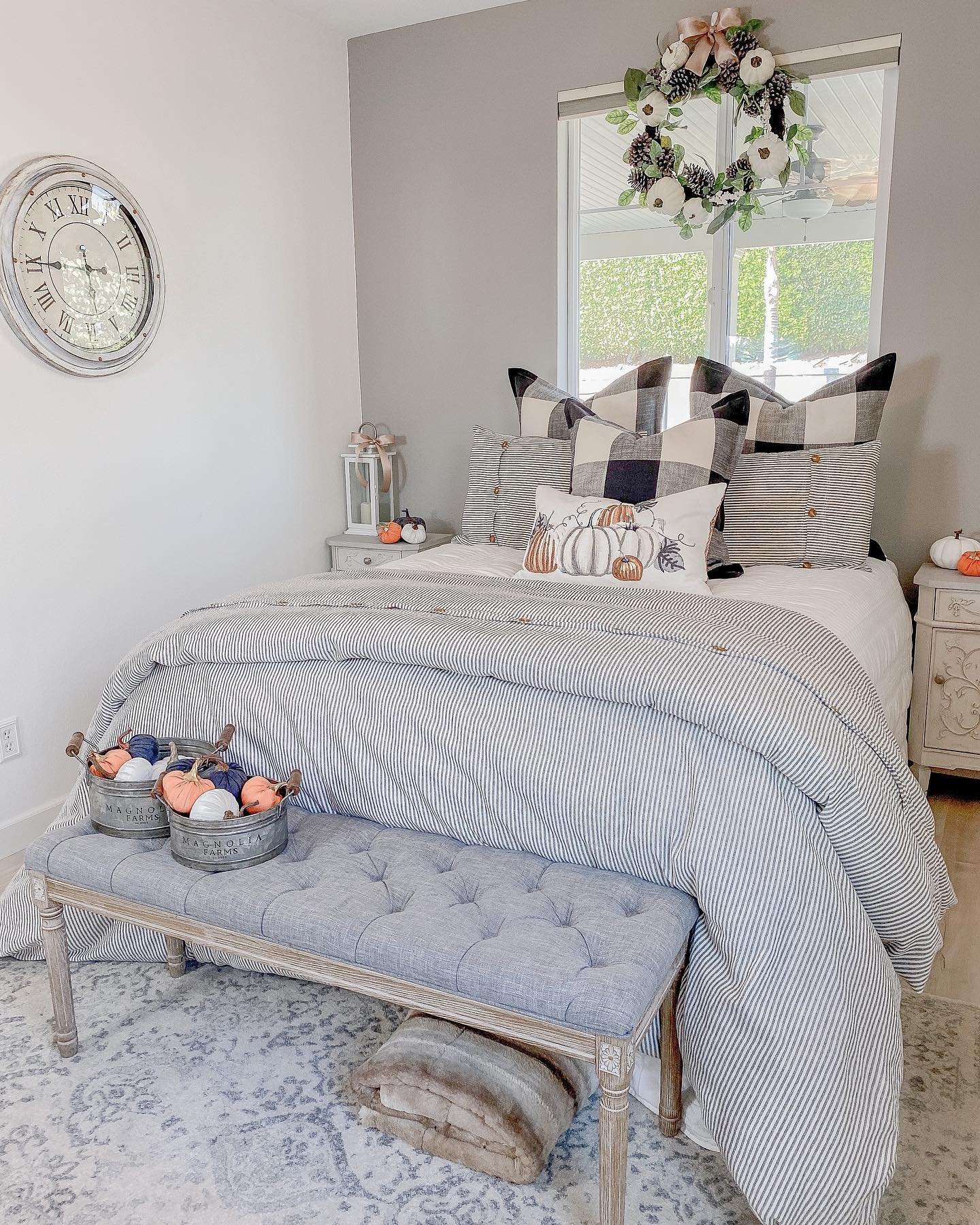 A bedroom with gray walls, a bed with a striped comforter, and farmhouse-style decor.