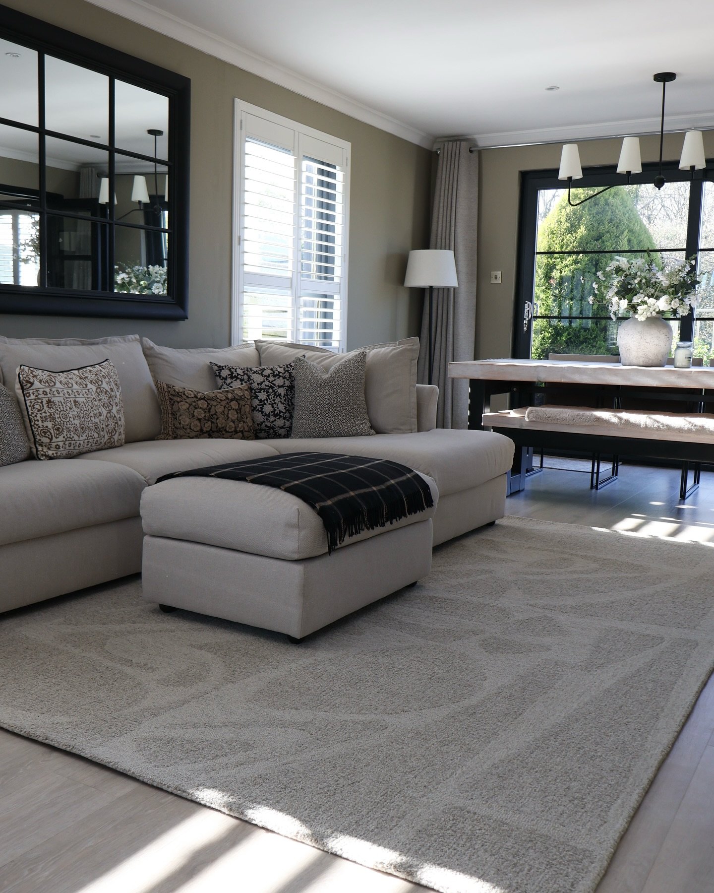 A light gray rug with a subtle, abstract pattern on a light wood floor in a living room.
