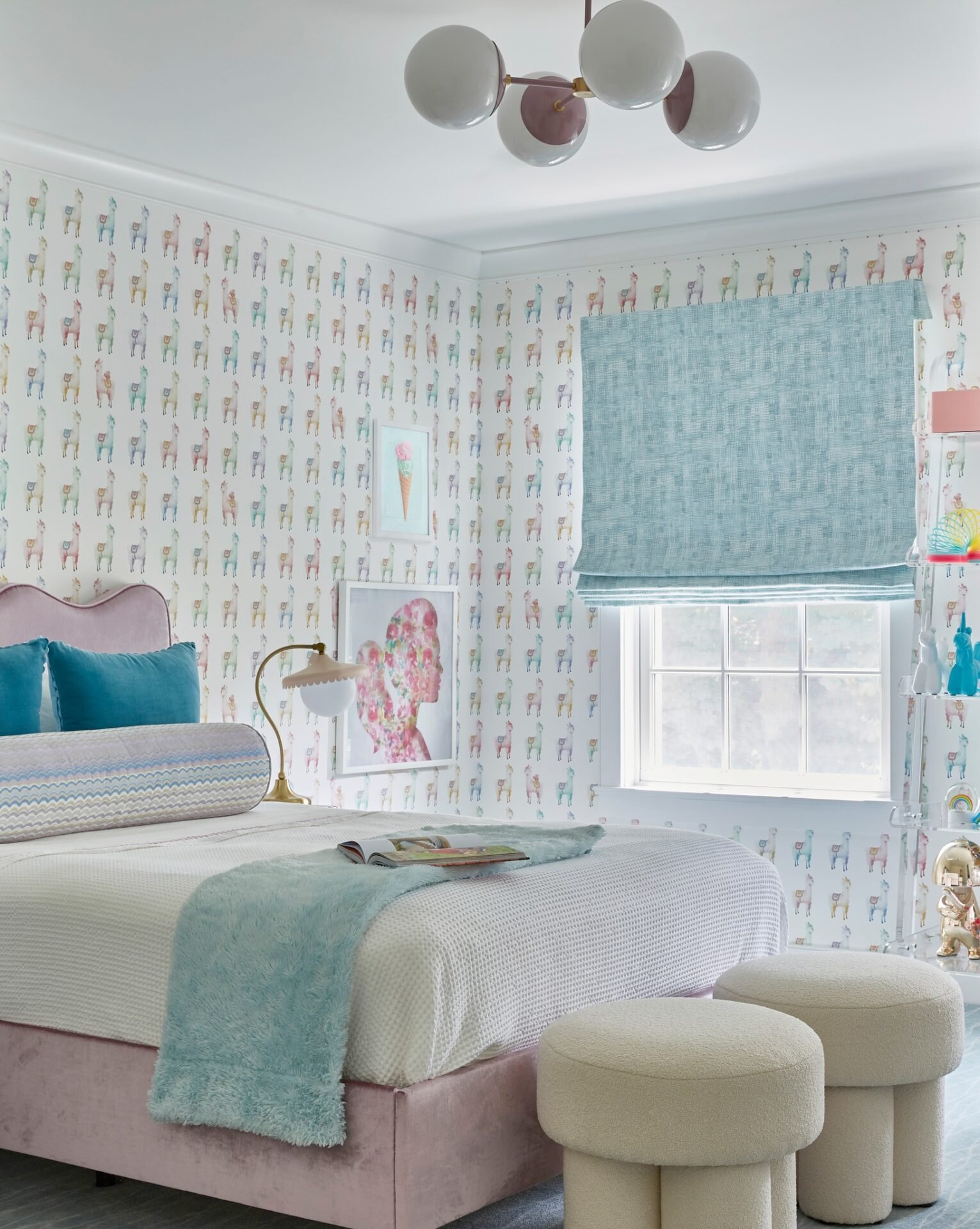 A colorful and whimsical girl's bedroom with light pink velvet bed, light blue blankets and an all-over giraffe-patterned wallpaper.
