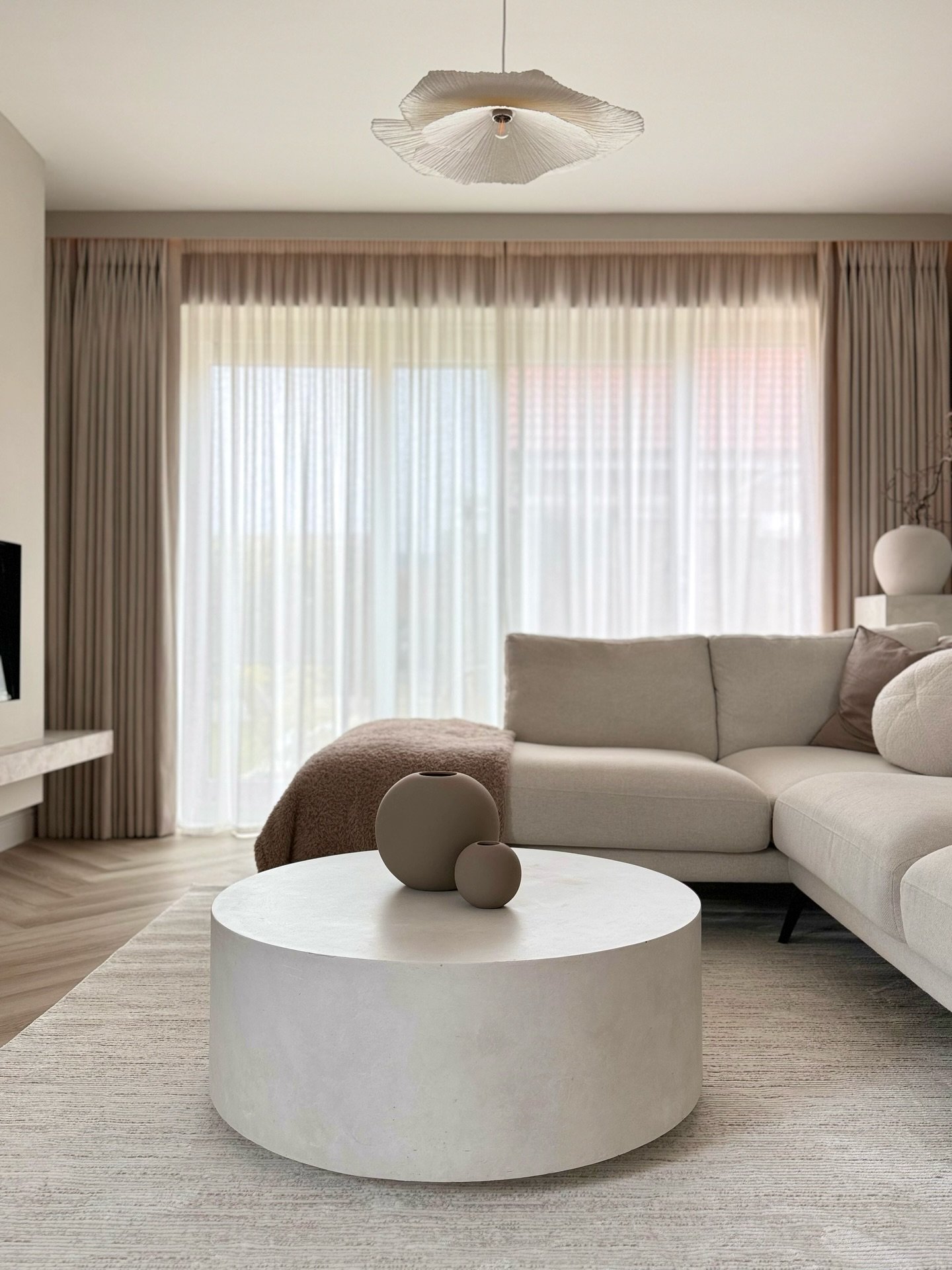 A light beige or off-white textured rug with a subtle pattern on a herringbone wood floor.