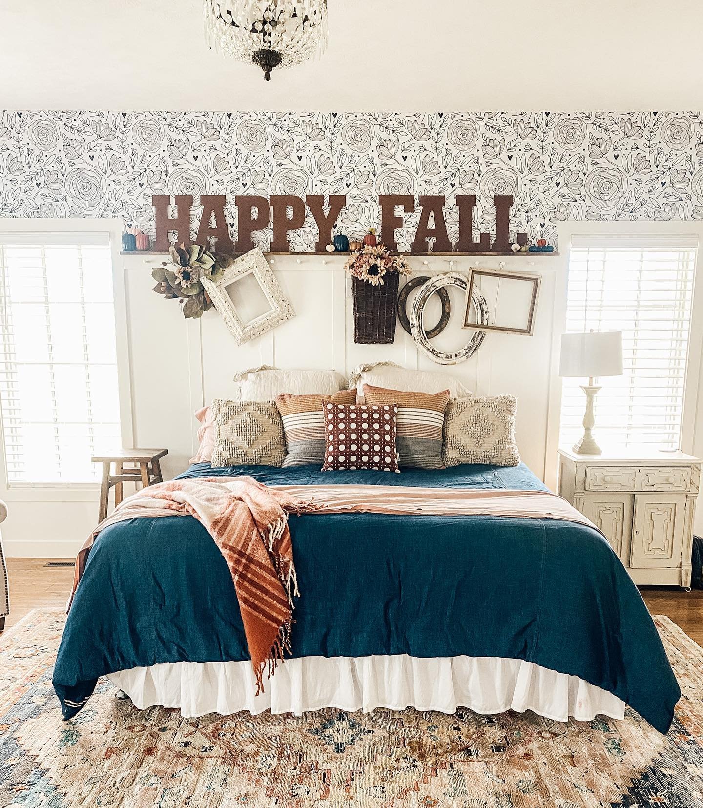  A bedroom with a "Happy Fall" sign above a bed with a dark blue comforter.