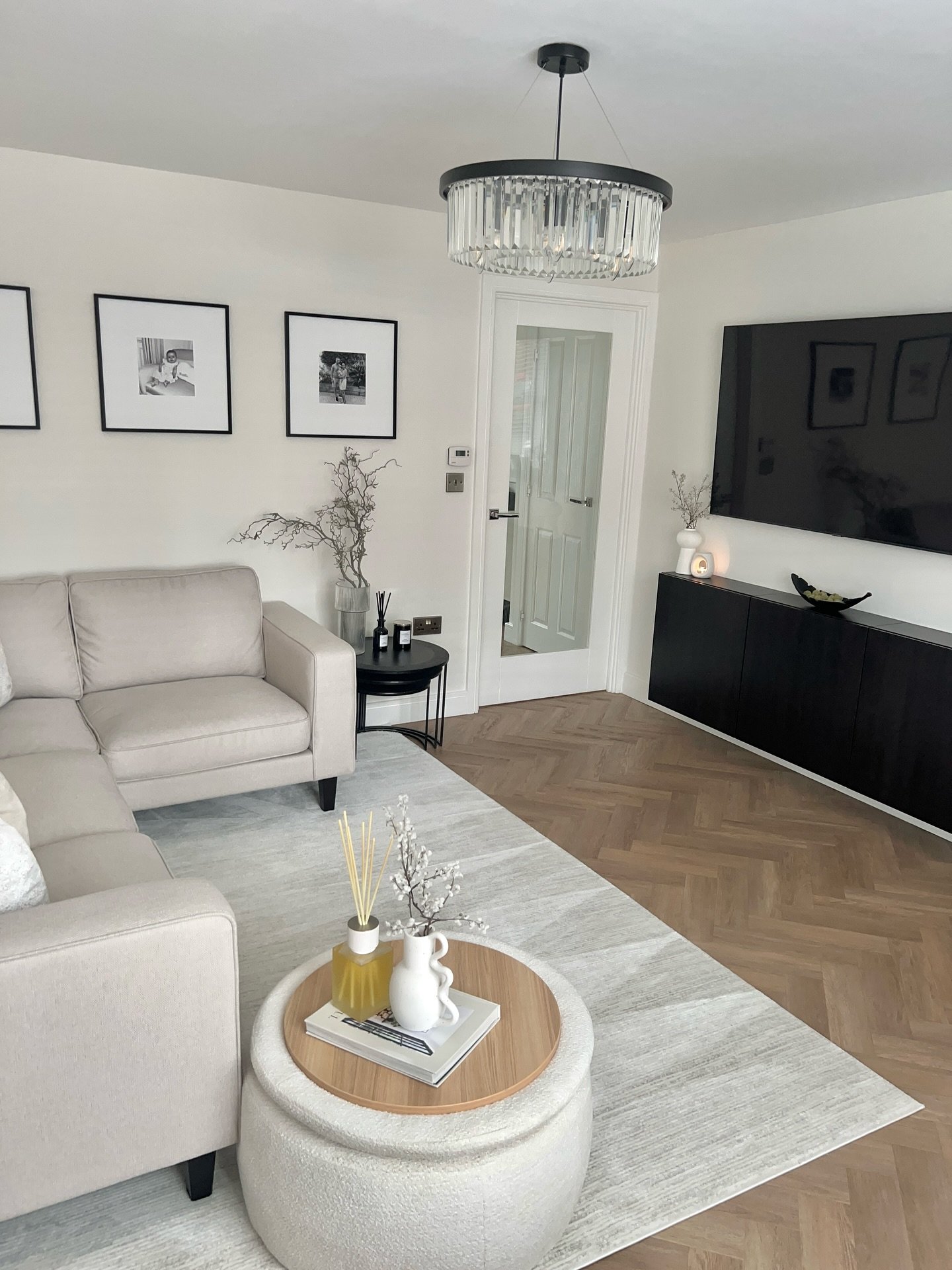 A light gray or off-white area rug with a subtle, abstract geometric pattern on a light herringbone wood floor.