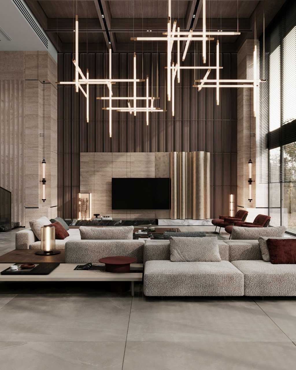 A vast, high-ceiling living room featuring a massive beige sectional sofa, a unique sculptural fireplace, and a dramatic, multi-level linear chandelier.