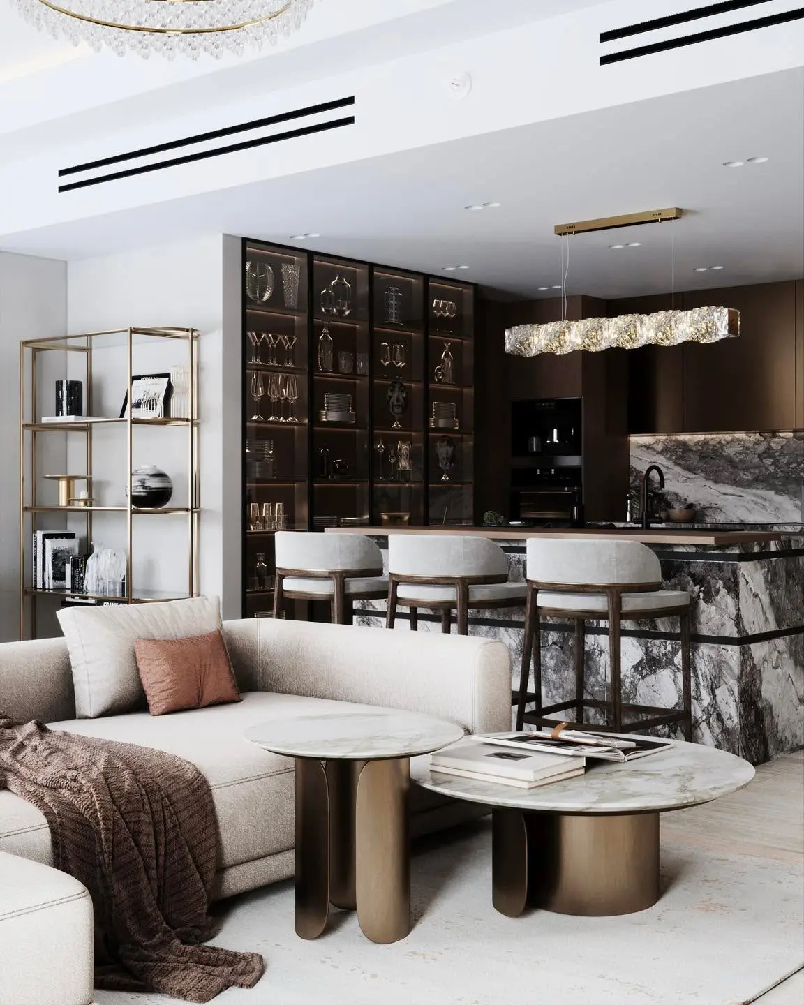 A high-end, open-concept living and kitchen area. The living room features a light-colored sectional sofa and two round marble-topped coffee tables. The kitchen has a stunning marble island with three bar stools, dark wood cabinetry, and a glass display case filled with decor.
