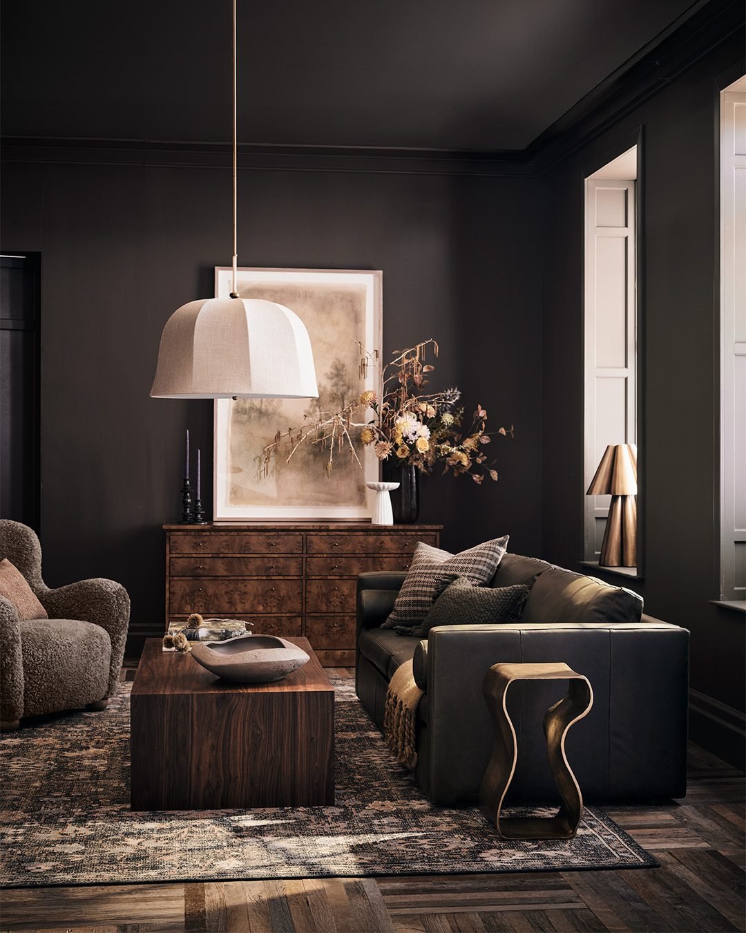 A dark, vintage-inspired area rug with a faded pattern in shades of brown, black, and gray on a dark wood floor.