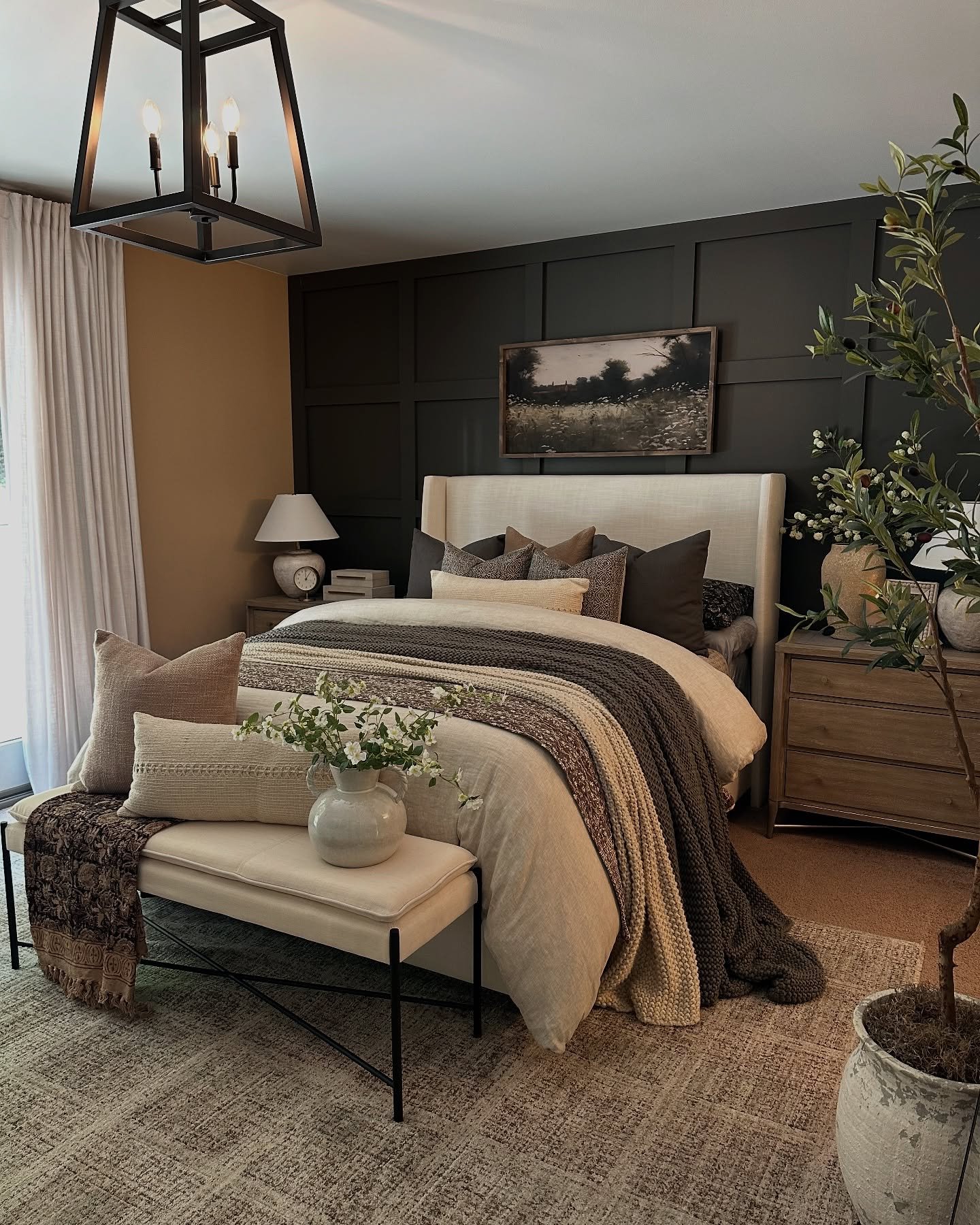 A neutral, textured area rug with a subtle pattern is placed under a bed and a bench with an upholstered top.