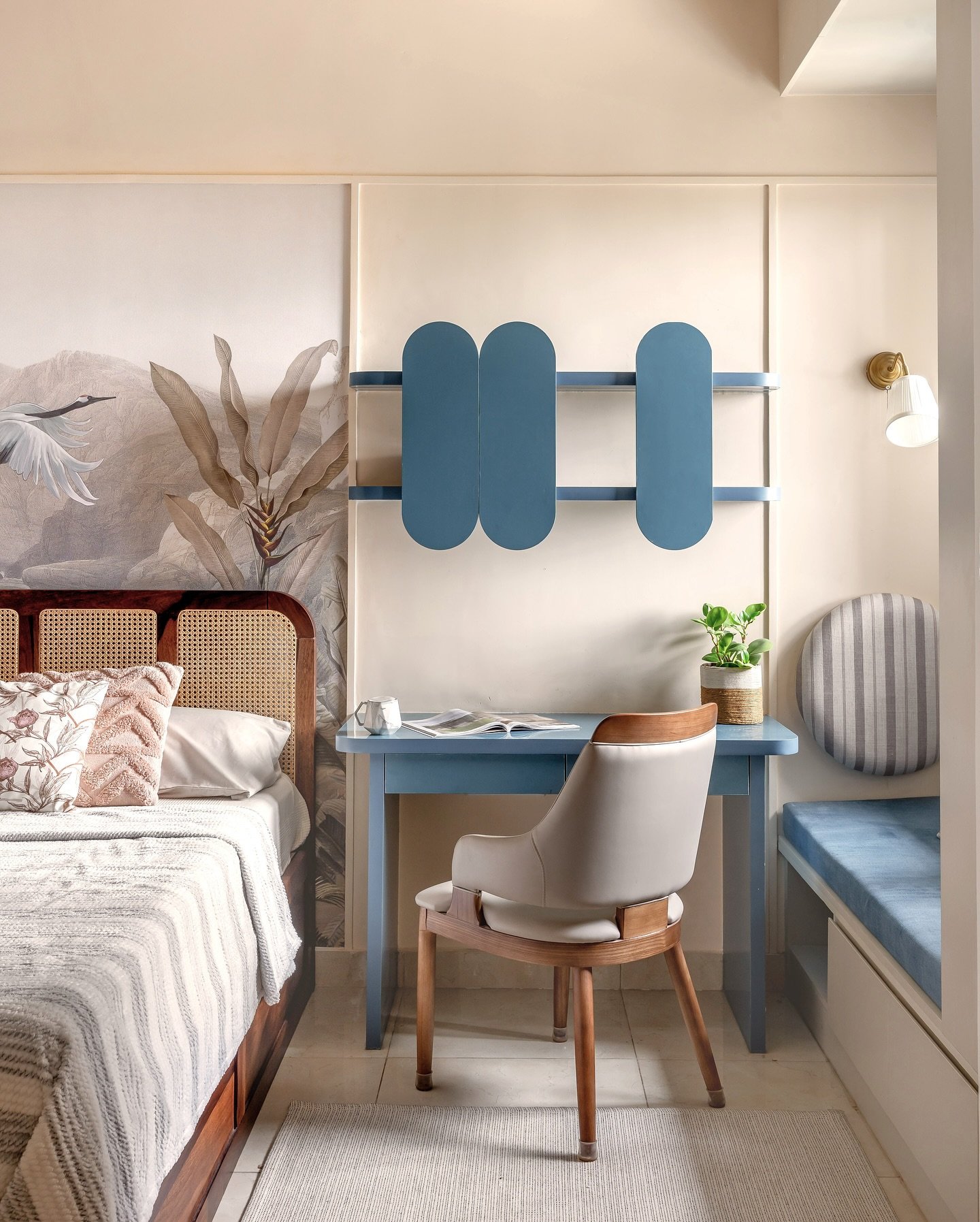 An artistic study table featuring a simple light-blue desk, a wooden chair, and a unique blue shelving unit with a whimsical design.