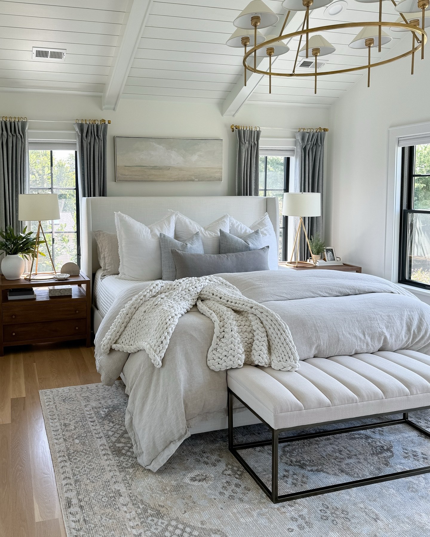 A light gray and white patterned area rug placed under a large bed with a white headboard and gray and white bedding.