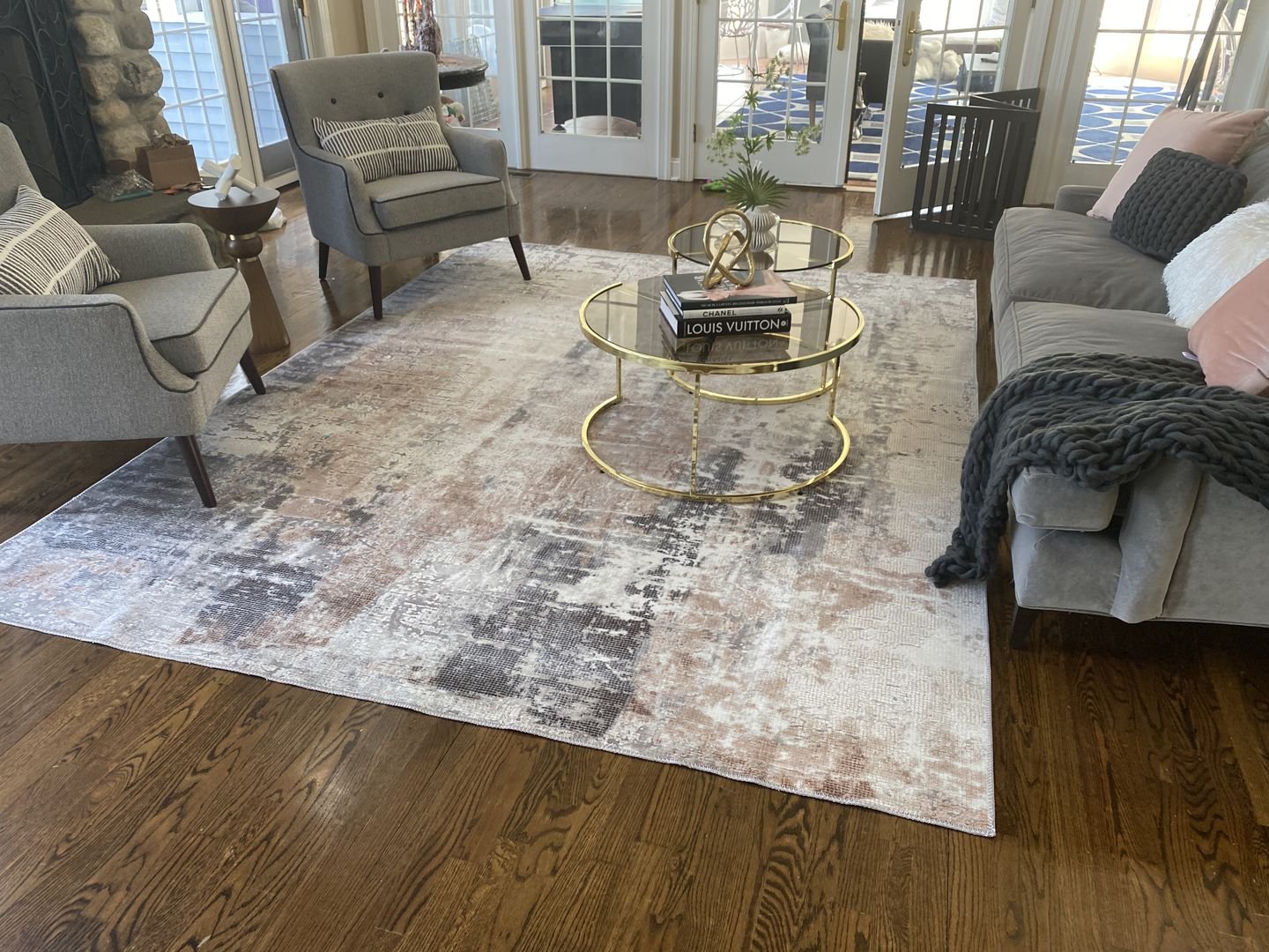 A large, abstract area rug with a painterly pattern in a blend of gray, white, and brown tones on a dark wood floor.