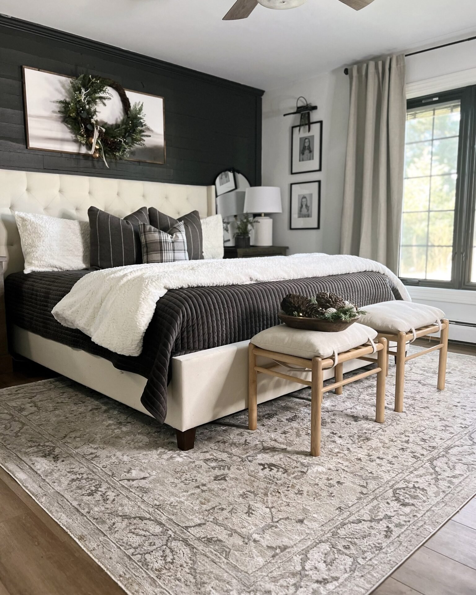 A large, ornate area rug with a distressed pattern in shades of gray and beige is placed under a large bed with a dark comforter and light pillows.