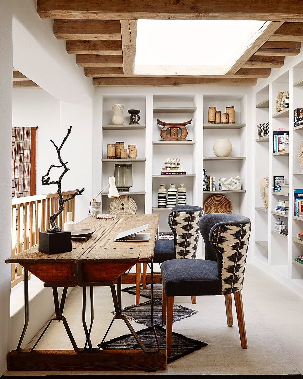 A rustic and industrial study desk with a thick wooden top, a dark metal base, and two chairs with patterned backs.