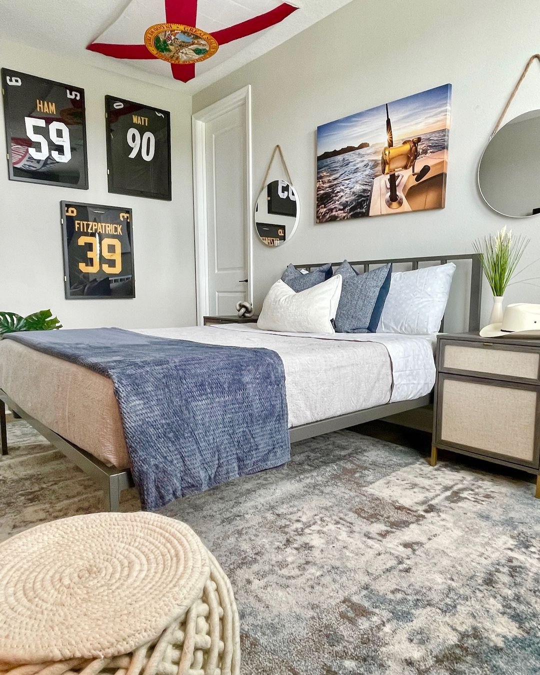 A teenage boy's bedroom with a sports theme and coastal elements, featuring framed football jerseys, a boat canvas print, and a fan with the Florida flag.