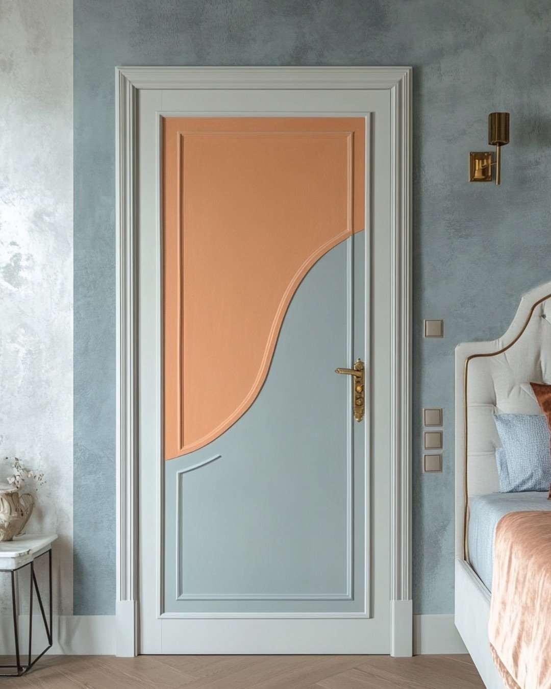 A unique bedroom door with a two-tone design, featuring a graceful, curved line separating a peach-colored top section and a pale blue bottom section, framed by classic white trim.
