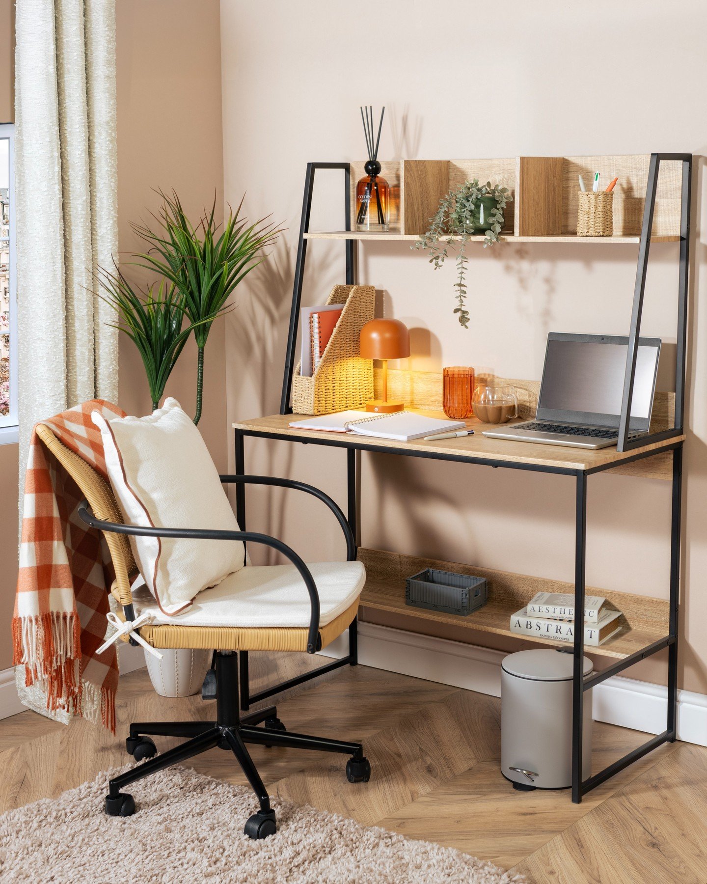 A modern ladder-style study desk with light wood shelves, a black metal frame, and a woven cane chair with a cushion.