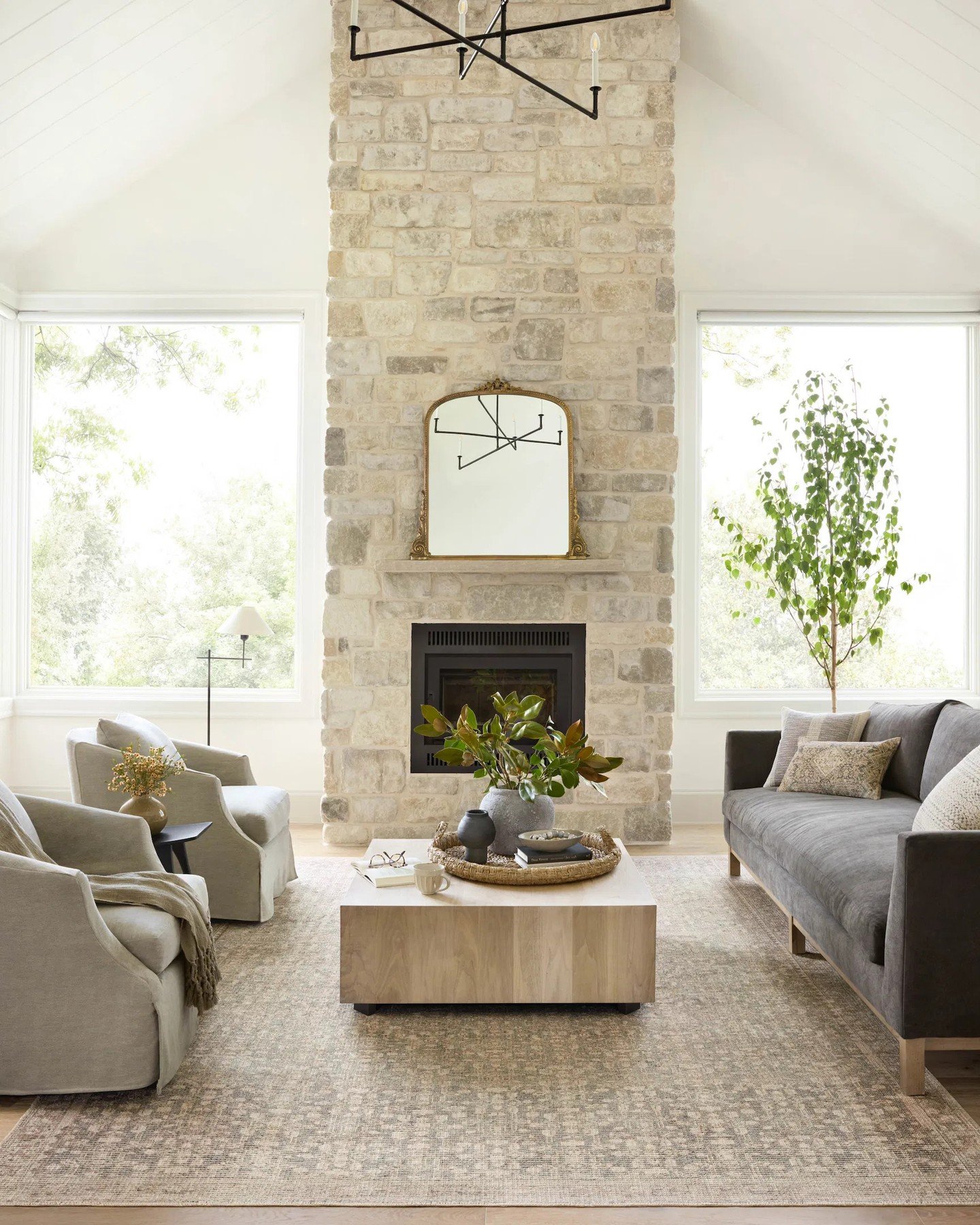 A light gray or beige rug with a subtle, geometric diamond pattern, placed on a light wood floor in a living room.