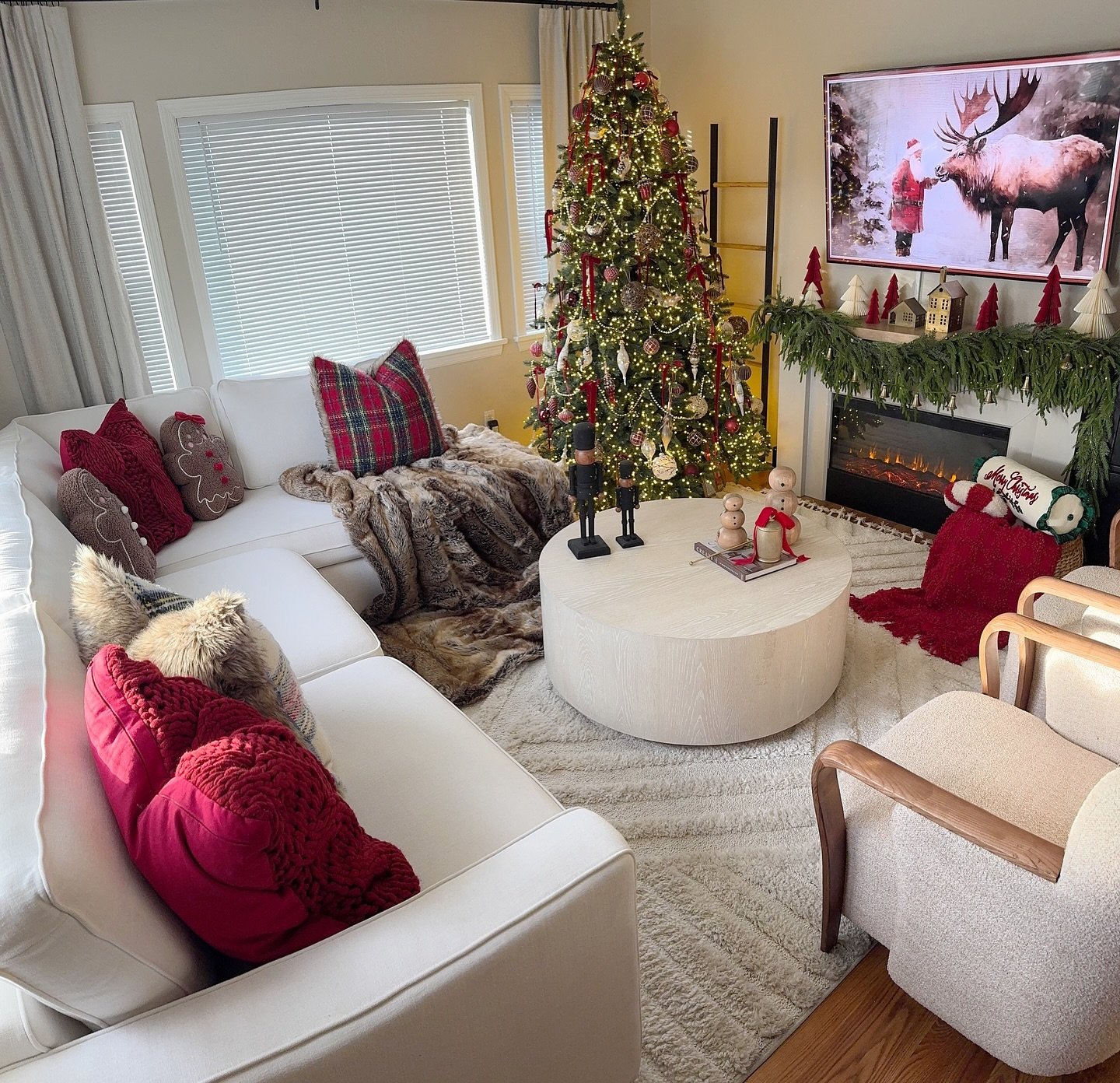 Bright living room with a large white sectional, fully decorated Christmas tree, and a mantel with classic garland.