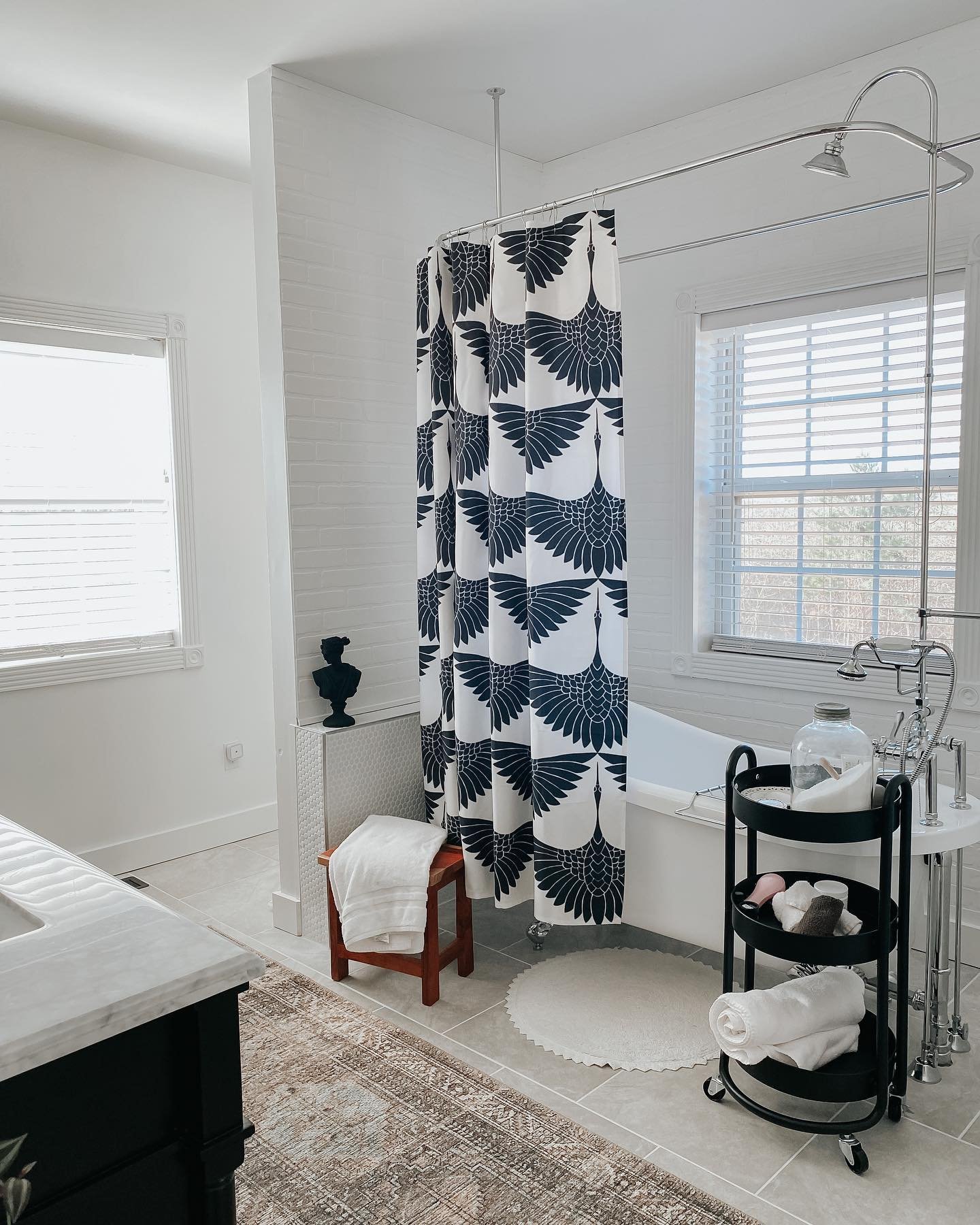 A crisp white shower curtain printed with a large, repeating, graphic pattern of navy blue or black Japanese cranes in flight.