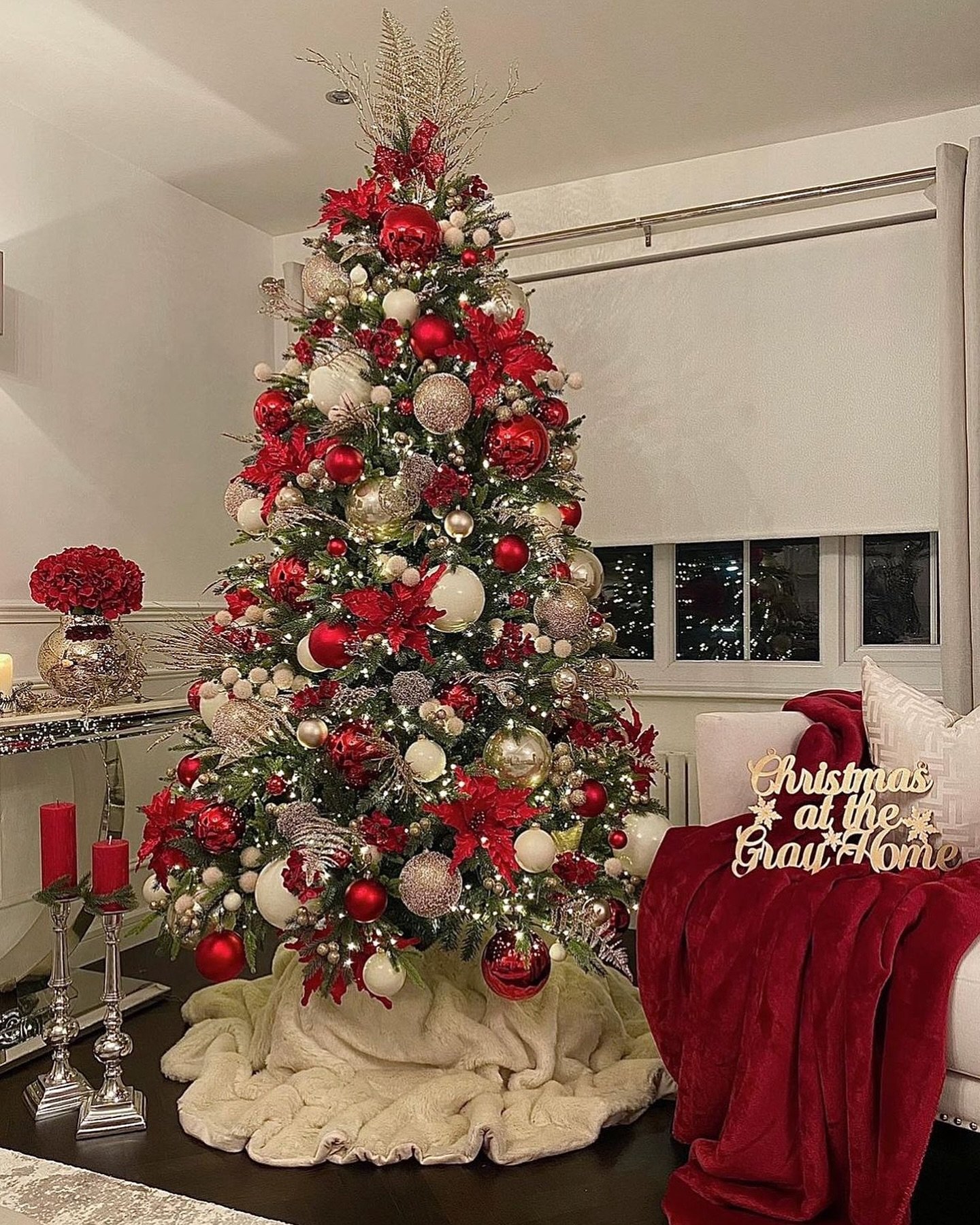 A lavish Christmas tree decorated in bold red, crisp white, and shimmering gold ornaments, with red poinsettias and sparkly picks.