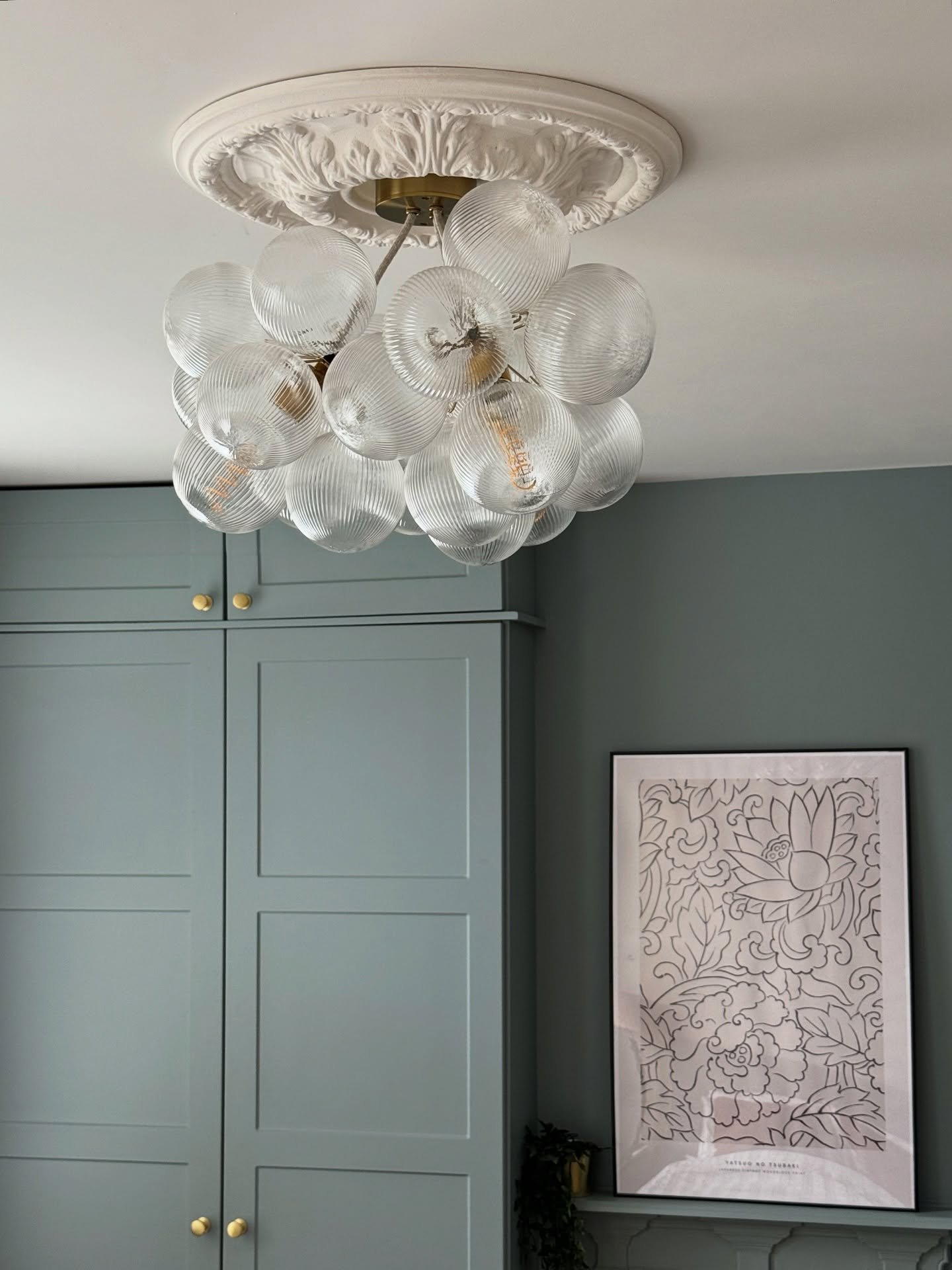 A unique chandelier composed of multiple ribbed clear glass globes clustered together hangs from a decorative ceiling medallion.