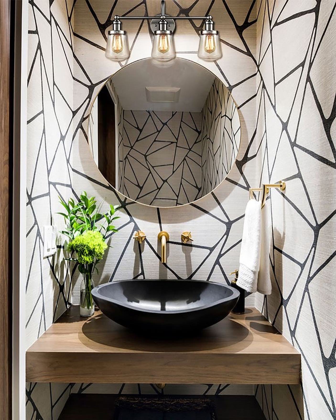 A small bathroom with a black, rounded rectangular vessel sink on a floating wooden vanity.
