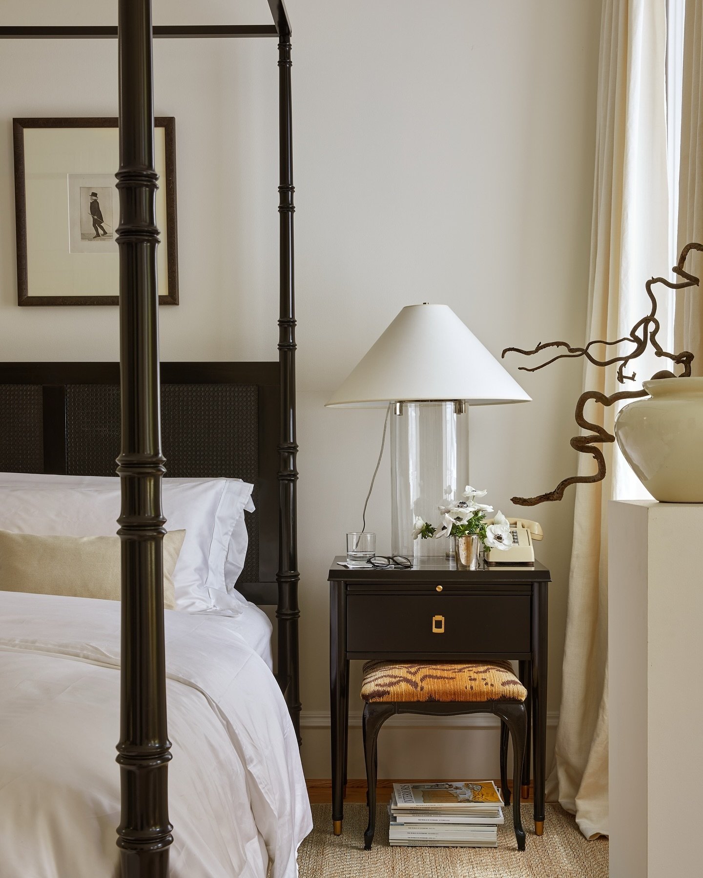 An elegant bedroom with a classic, bell-shaped lampshade on a tall, cylindrical glass base.