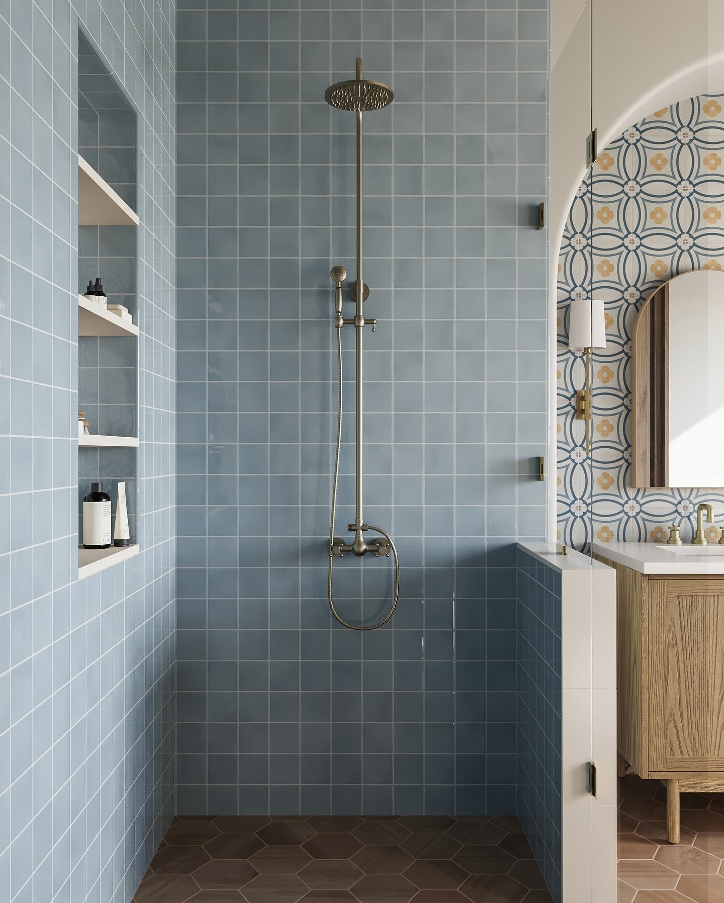 A bathroom with a walk-in shower. The shower walls are tiled with solid light blue square tiles, while the wall outside the shower features a yellow and blue geometric Moroccan-style pattern.