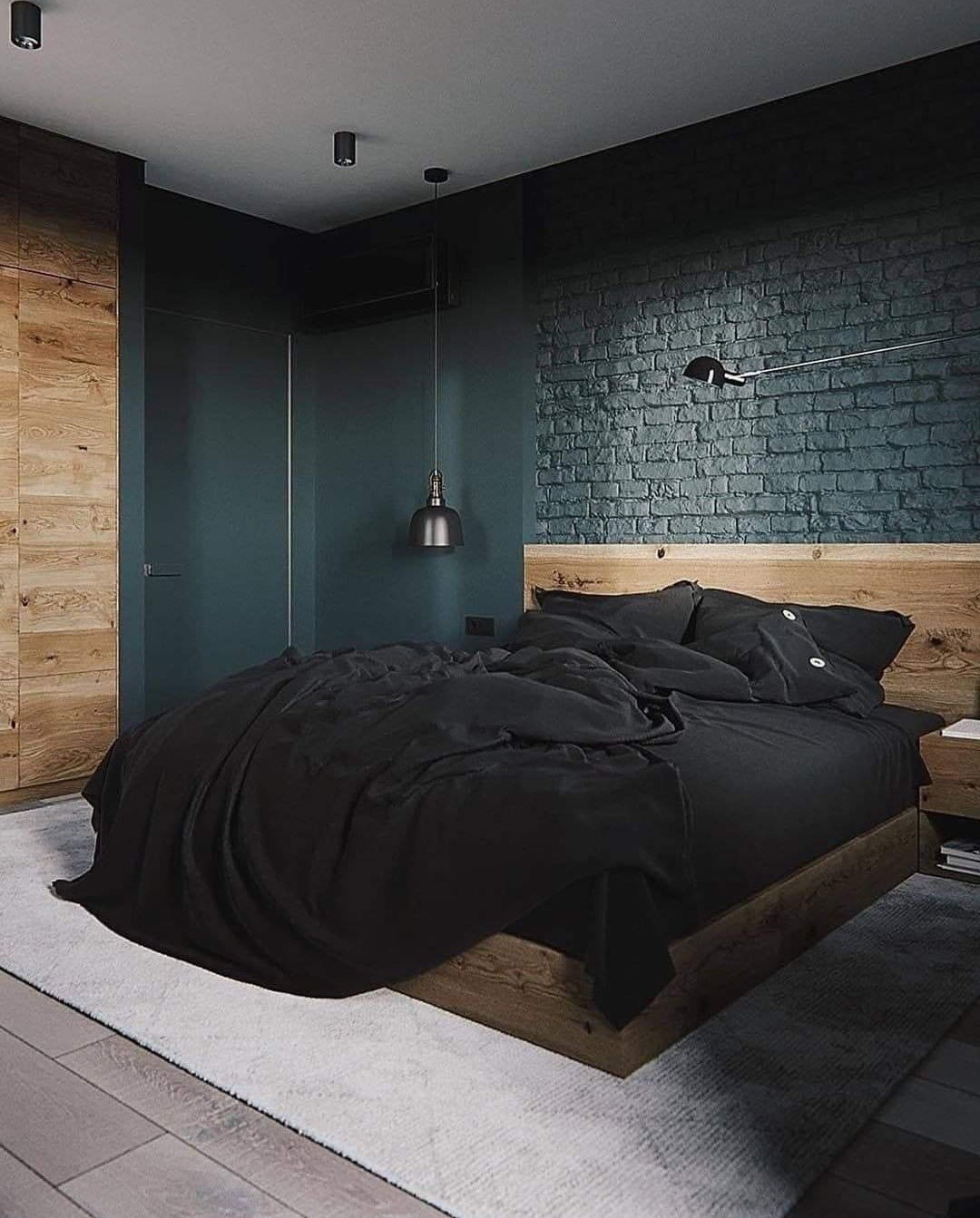 A bedroom with a dark black brick wall, a light wood bed frame and headboard, and a large black duvet.