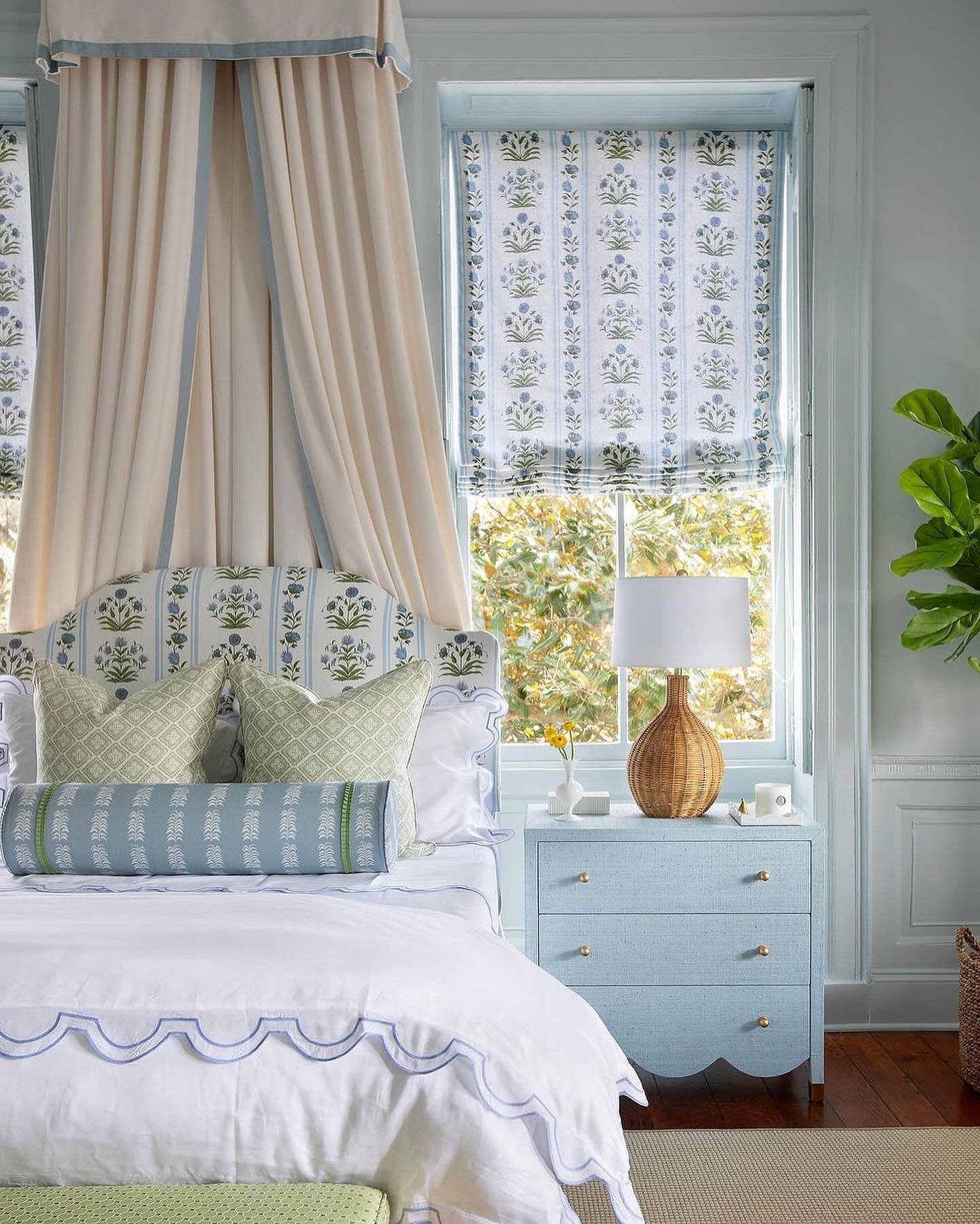 A coastal or cottage-style bedroom with a woven rattan-based lamp on a light blue nightstand.