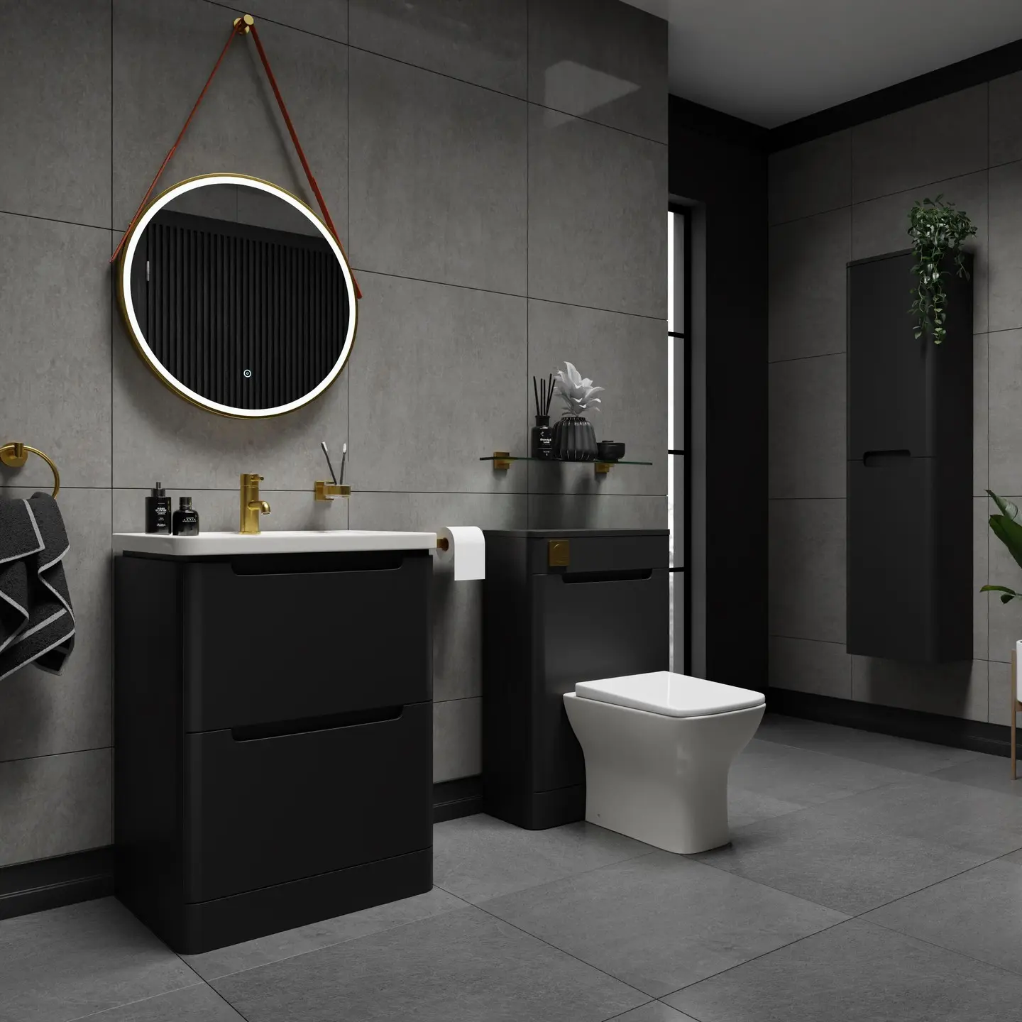 A bold, matte black bathroom vanity with two drawers and a white integrated sink. It is paired with a round backlit LED mirror with a gold frame and a red strap, gold fixtures, and a black toilet cabinet, against a dark gray tiled wall.