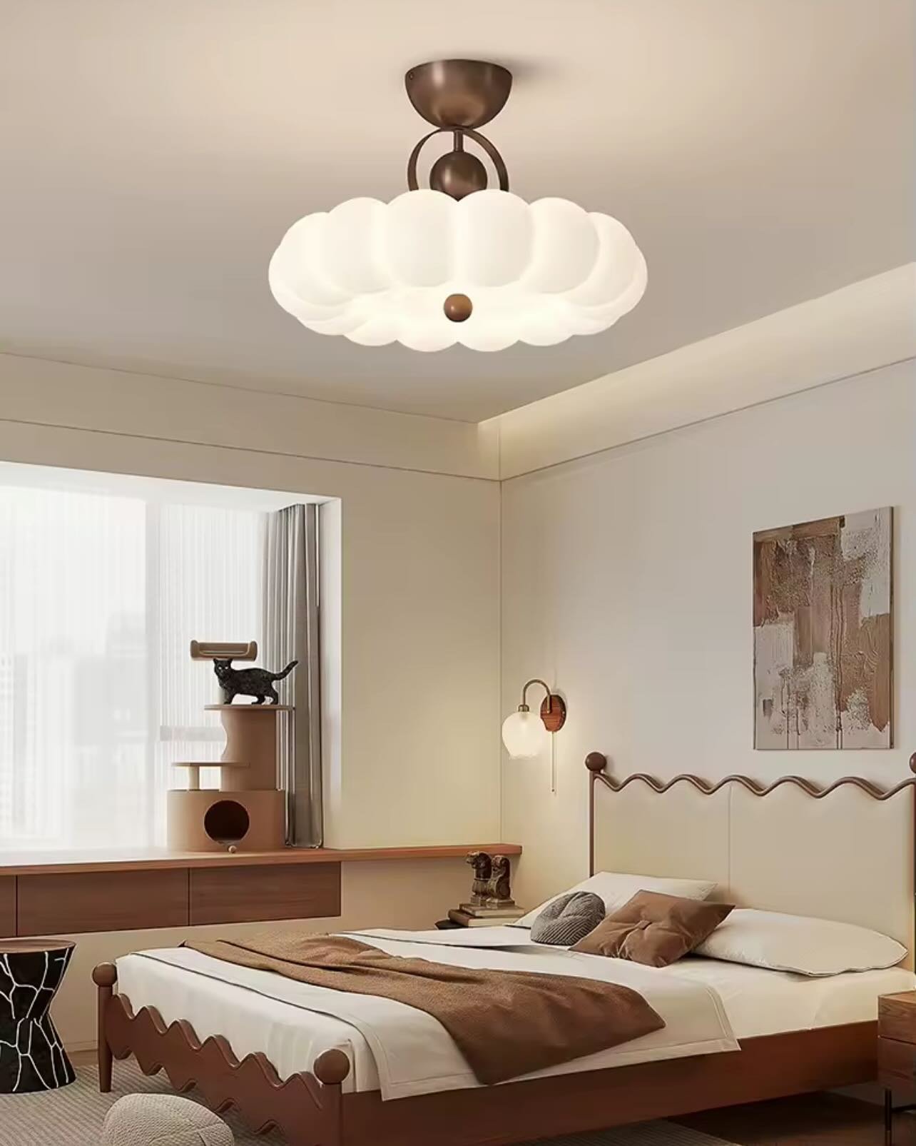 A unique, modern flush mount ceiling light with a fluffy, cloud-like shape hangs over a bed in a light-filled bedroom.